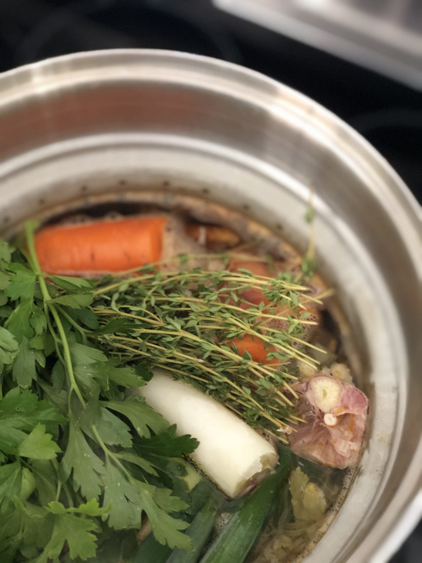 Chicken Stock in the pot Fresh vegetables, herbs and chicken bones simmer away in a large stainless steel pot