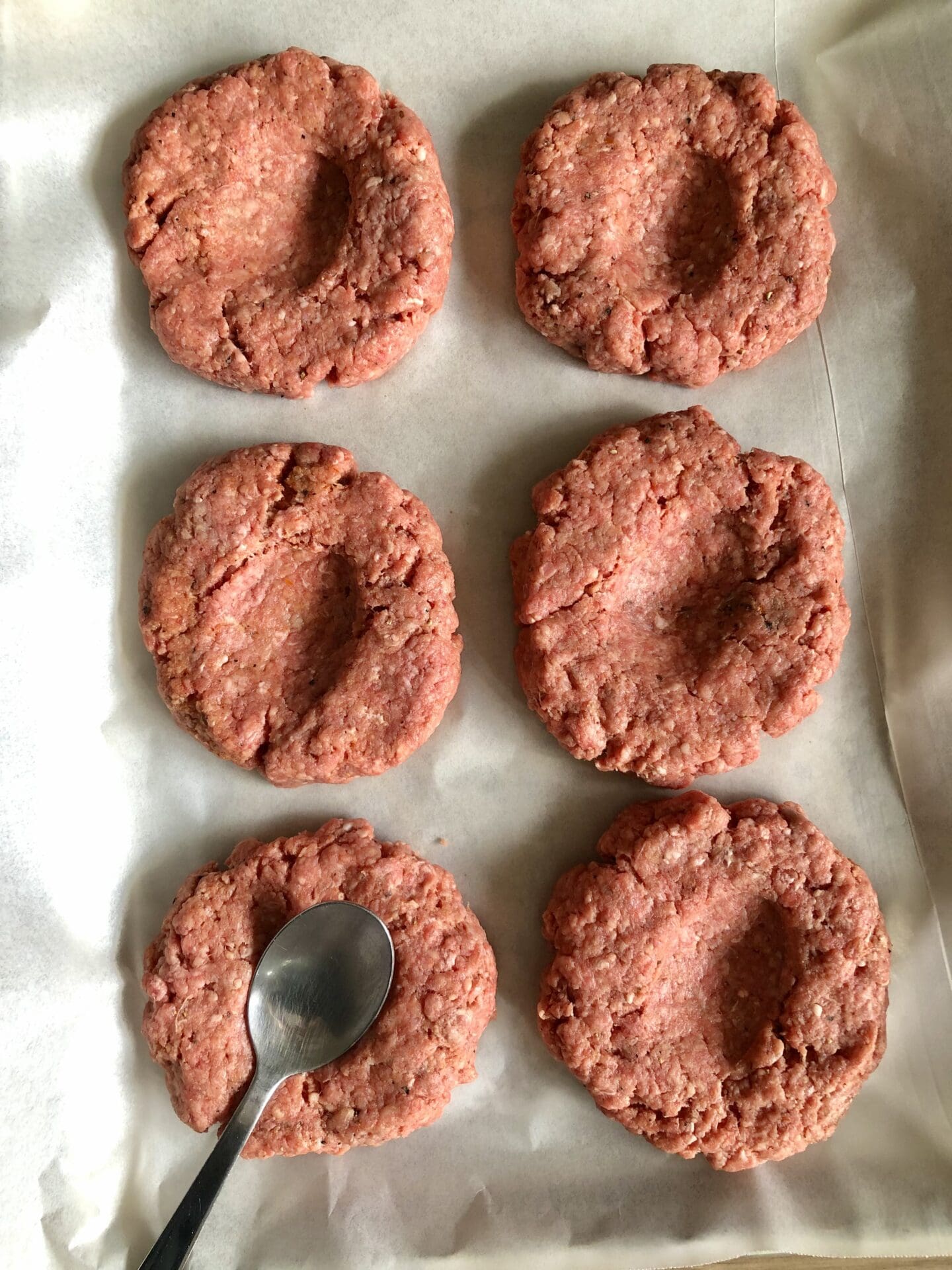 BB292346-951B-4722-BF59-F381A276163A Uncooked beef burger patties on a tray with indentations