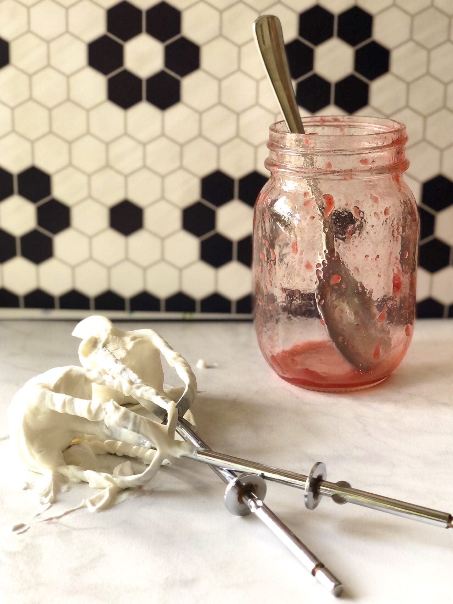697688B3-1015-45A3-93E7-85B47BA130C7 Empty strawberry sauce jar and beaters covered in whipped cream