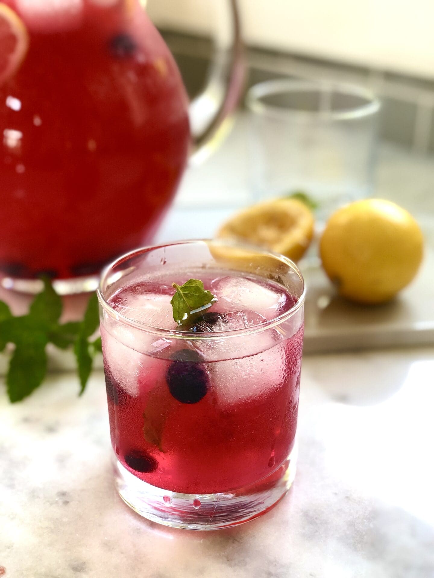 2B930121-8890-4EBC-BA0E-865E12C579DA Glass filled with blueberry lavender lemonade garnished with ice blueberries and mint leaves