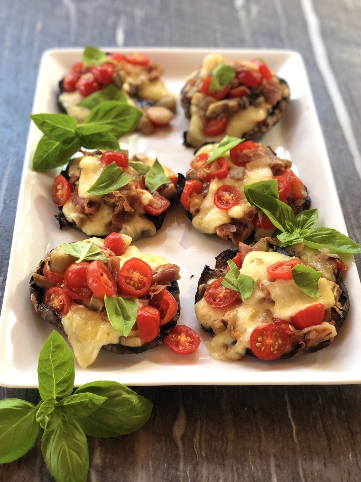 58395FFB-94B9-422B-B52C-1EA9934A6790 Platter of grilled stuffed portobello mushrooms with cheese, tomato and fresh basil