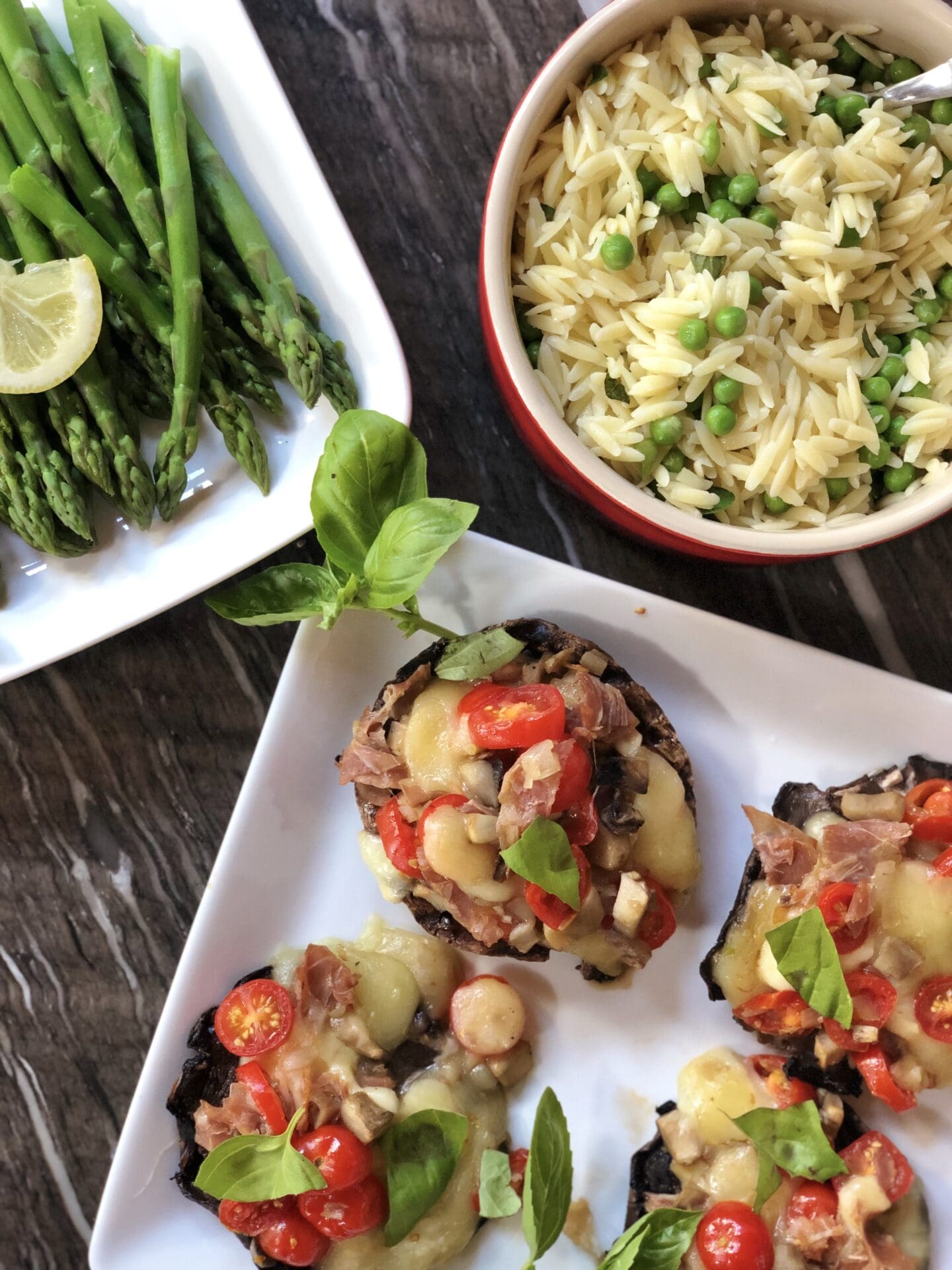 7F291B8F-2819-4B88-9209-B12B6E2F91F3 Bowls and platters of stuffed mushrooms, orzo pasta and asparagus