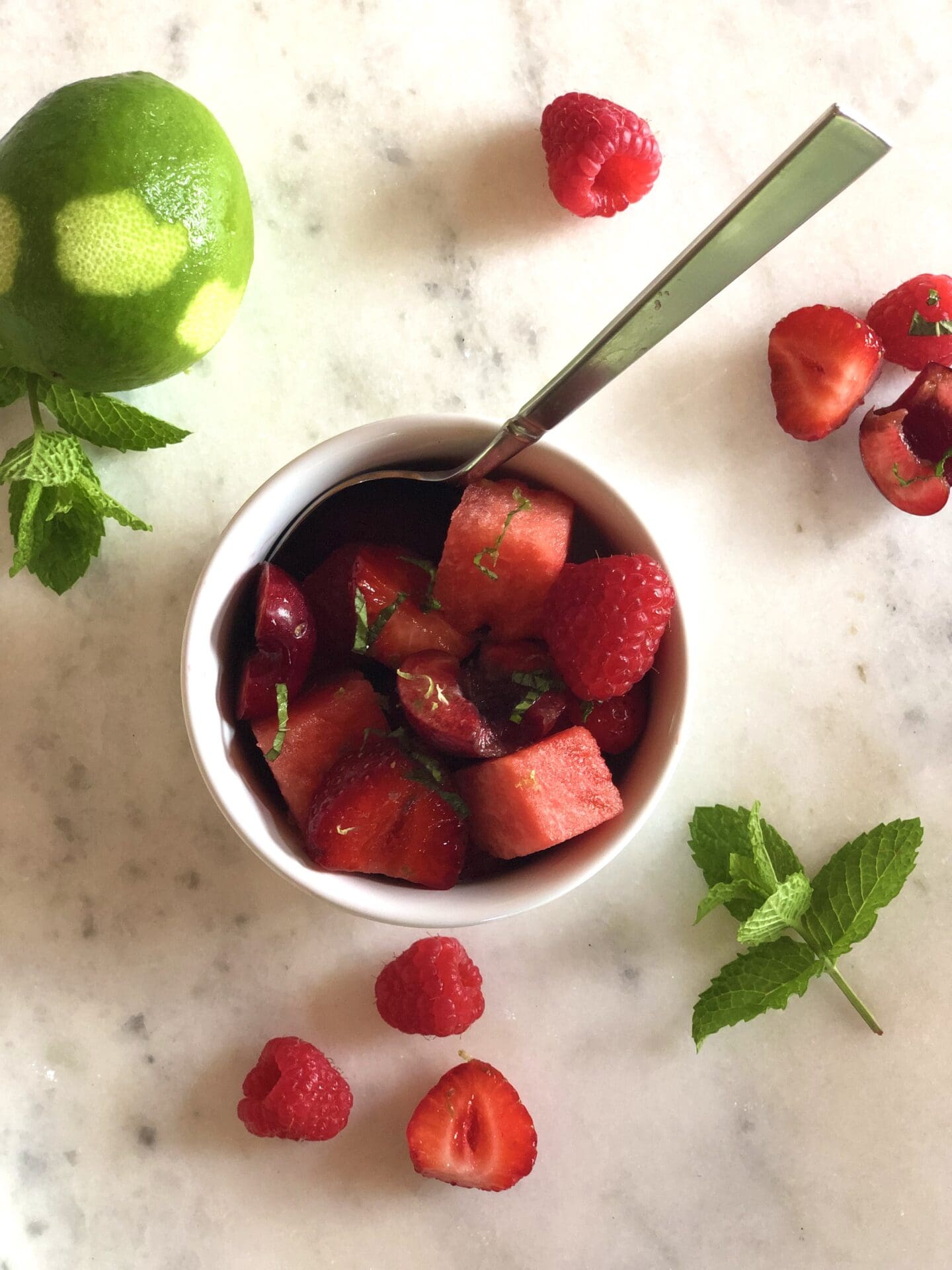 8B9334D1-2A09-4EBC-AE17-51D927EA7E6E Small bowl of red fruit salad with berries lime and mint