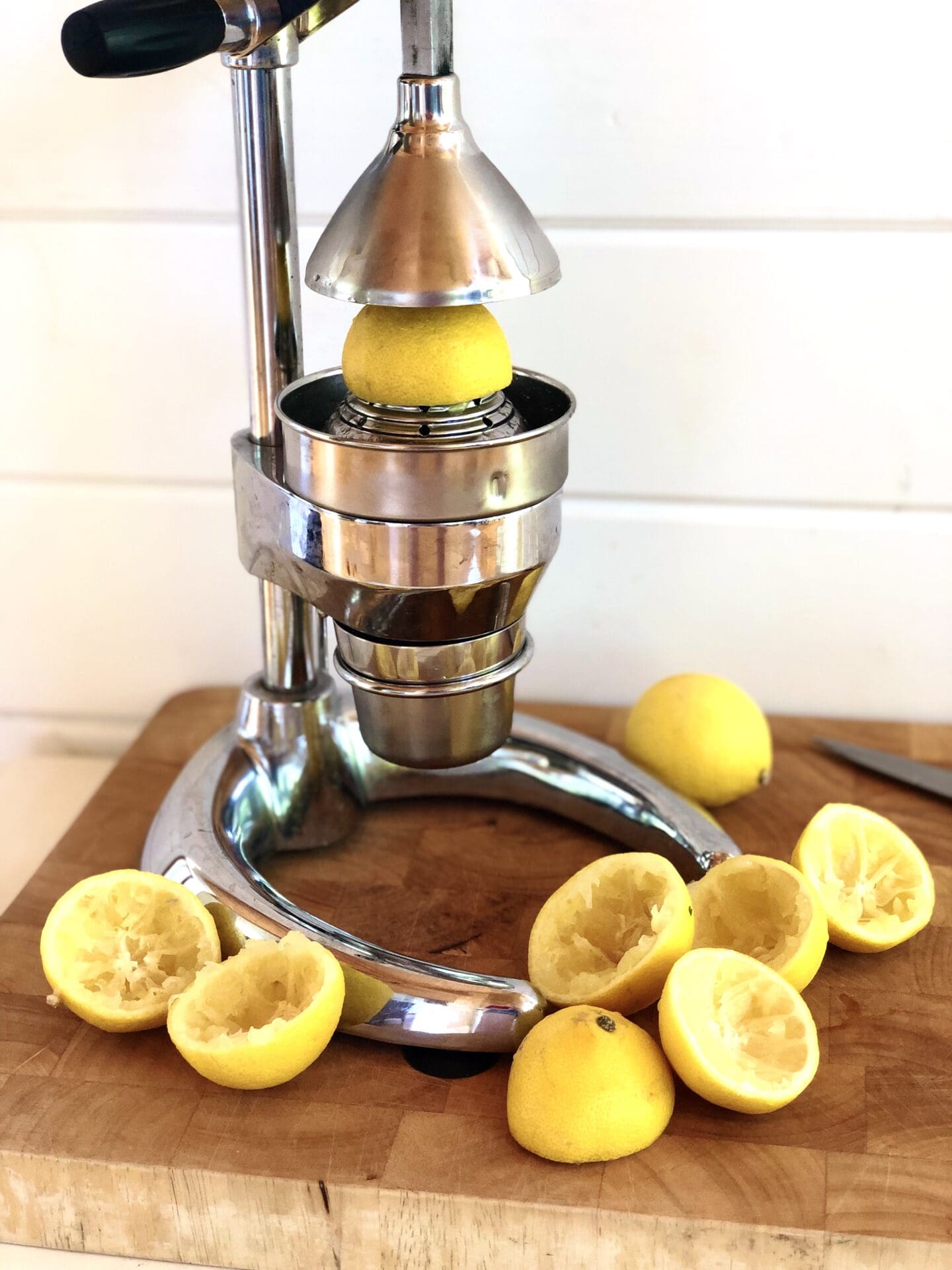 EE15FF9D-1033-4498-8062-7C6F51143F86 Citrus press with lemon rinds on a butchers block