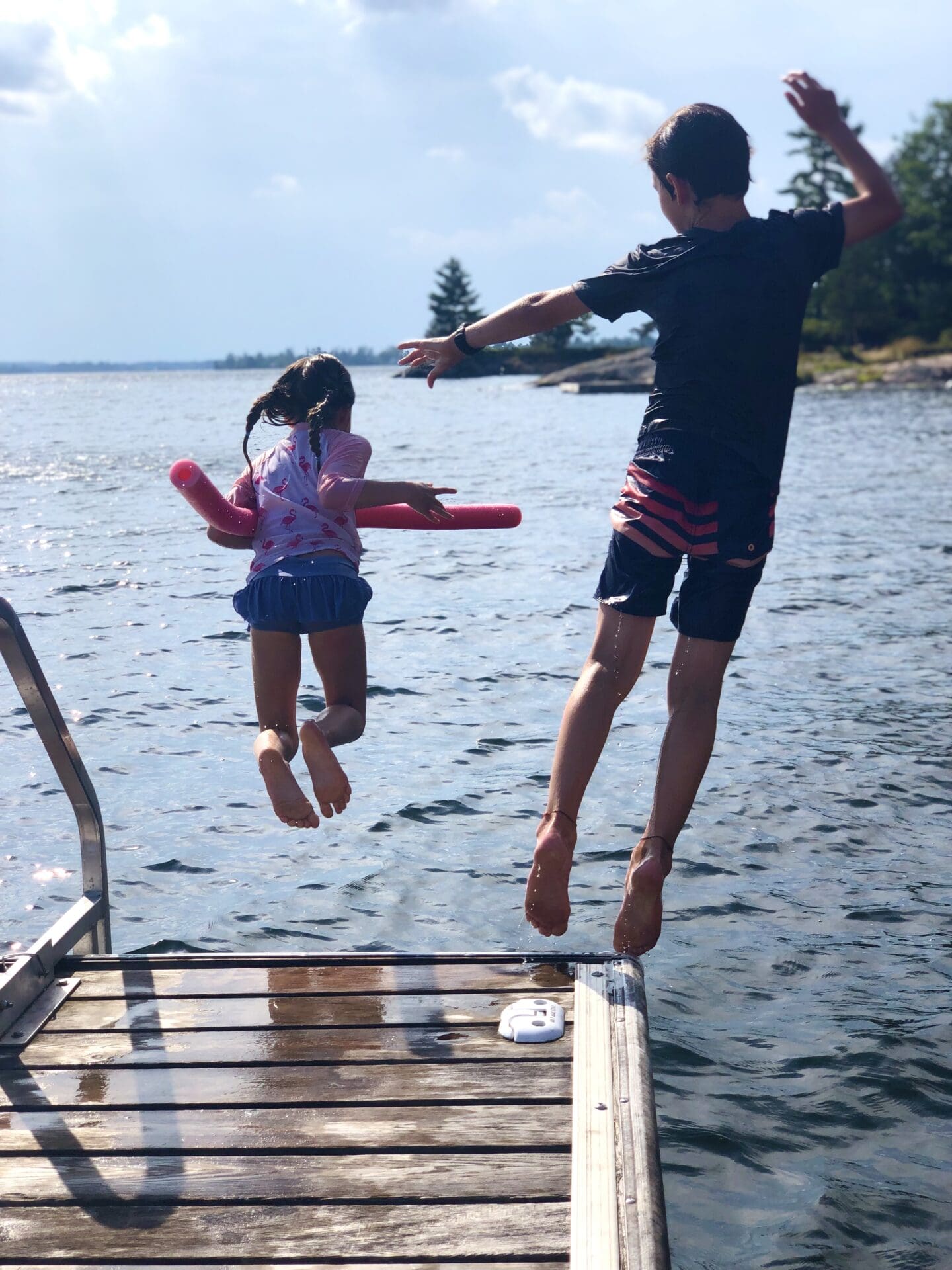 Kids jumping off a dock into a lake