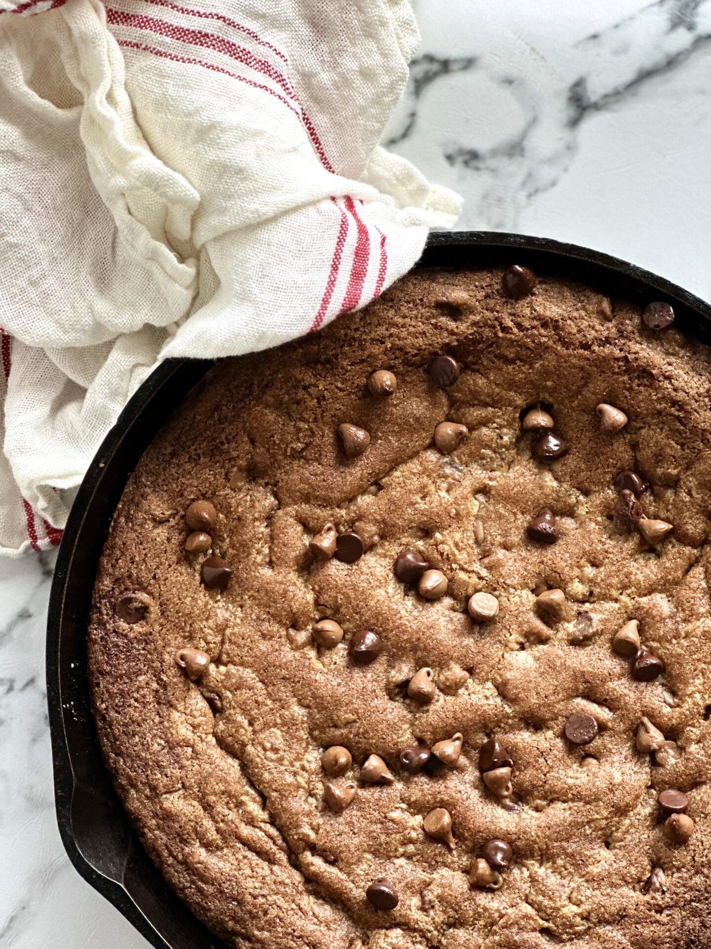FA8CE0D2-7303-4C94-BB88-E42DF41FC44D Giant deep dish chocolate chip skillet cookie warm from the oven in a cast iron pan