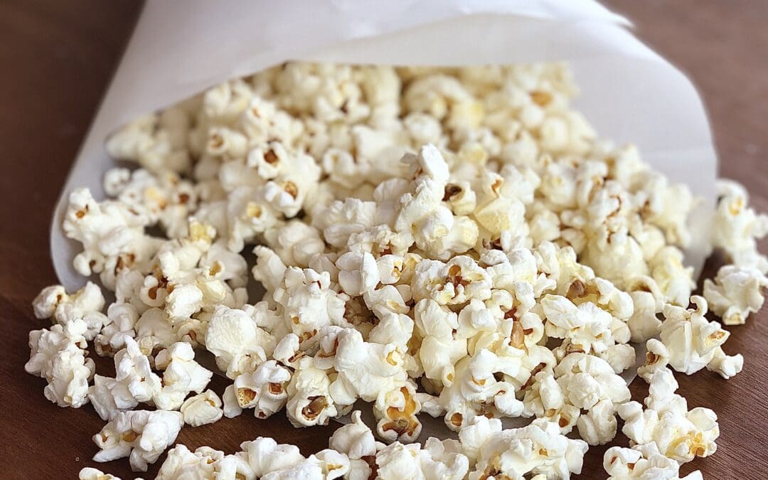 Paper cone of truffle popcorn spilling out onto a wood table