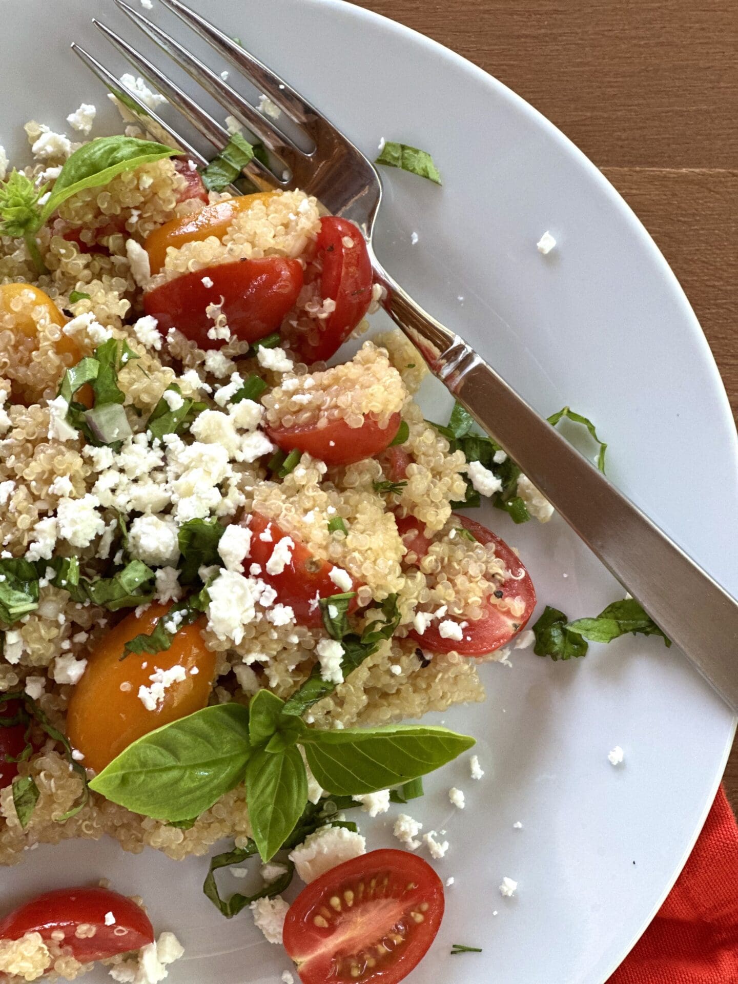 IMG_8925 A close up image of cherry tomato quinoa salad garnished with crumbled feta cheese and fresh basil