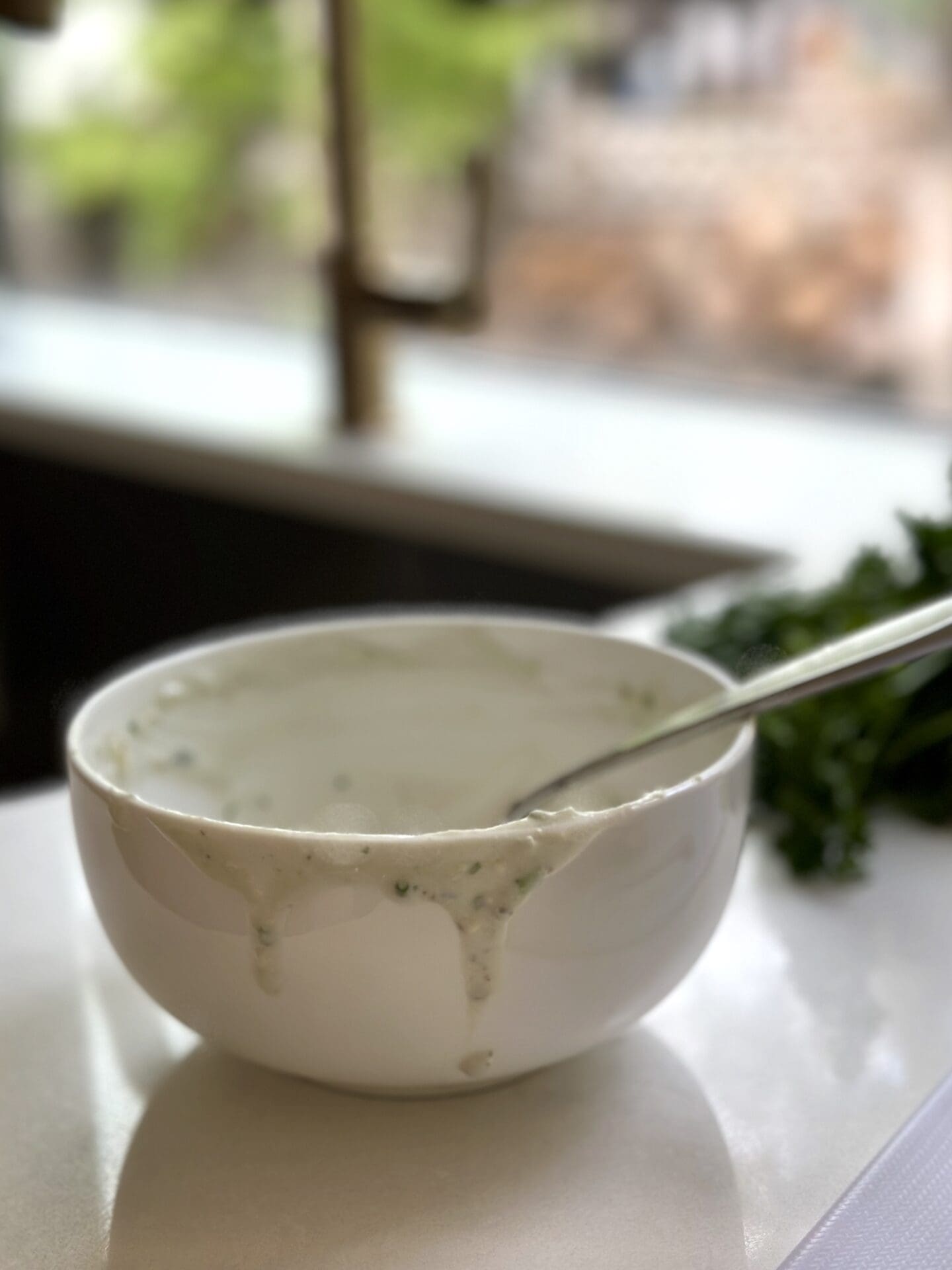IMG_9327 An empty bowl of homemade blue cheese dressing with drips coming down the side, sitting by a sink