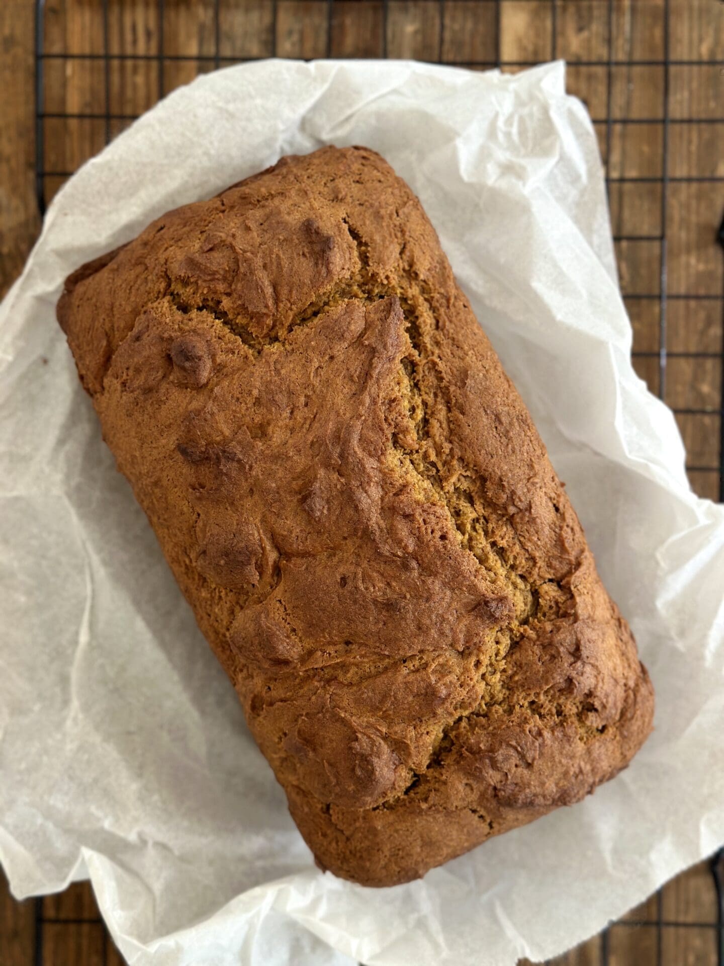 IMG_9714 A golden loaf of pumpkin bread fresh from the oven is cooling on a parchment paper lined rack