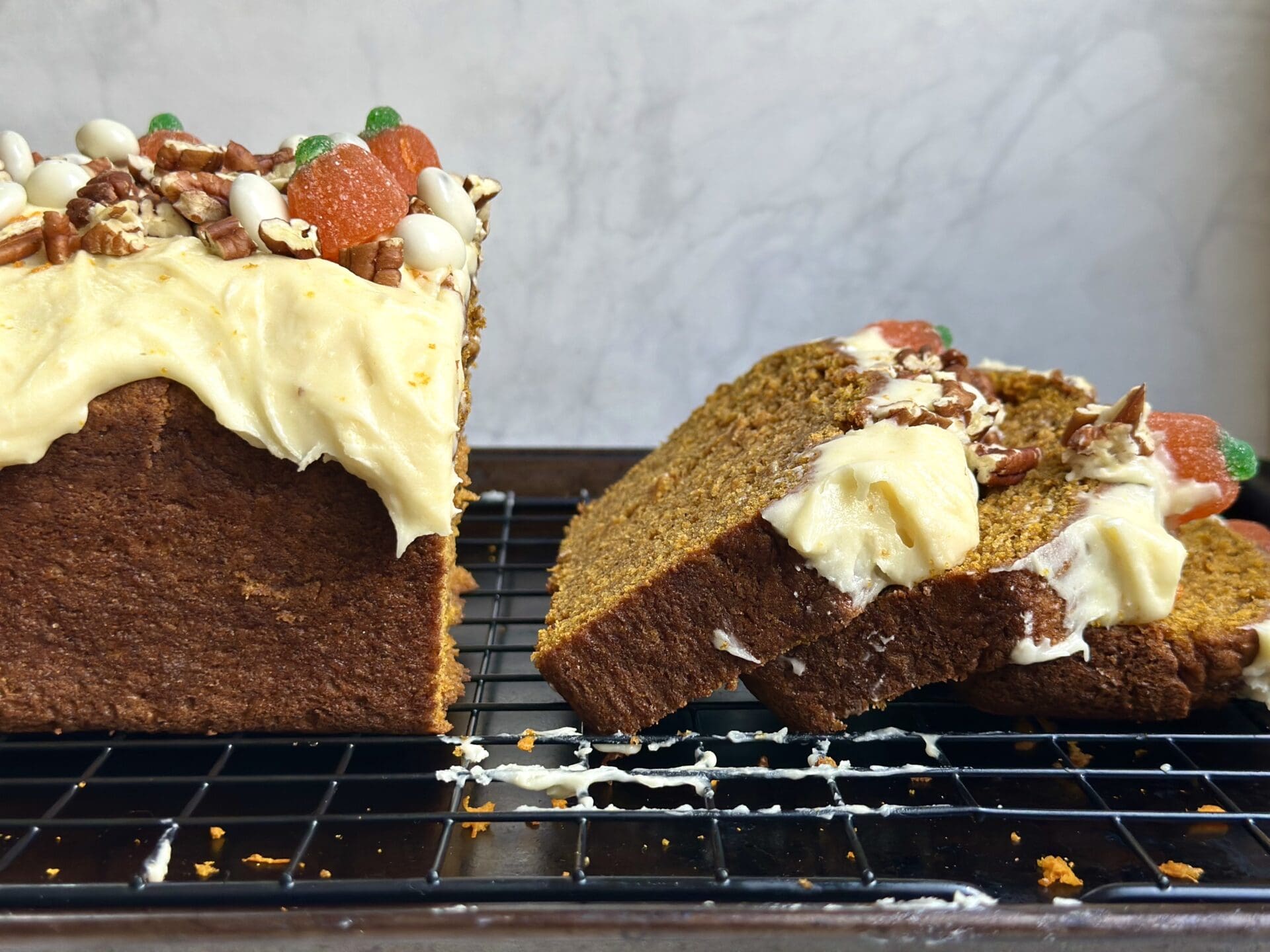 IMG_9760 A loaf of pumpkin bread with orange cream cheese frosting is sliced and seen from the side