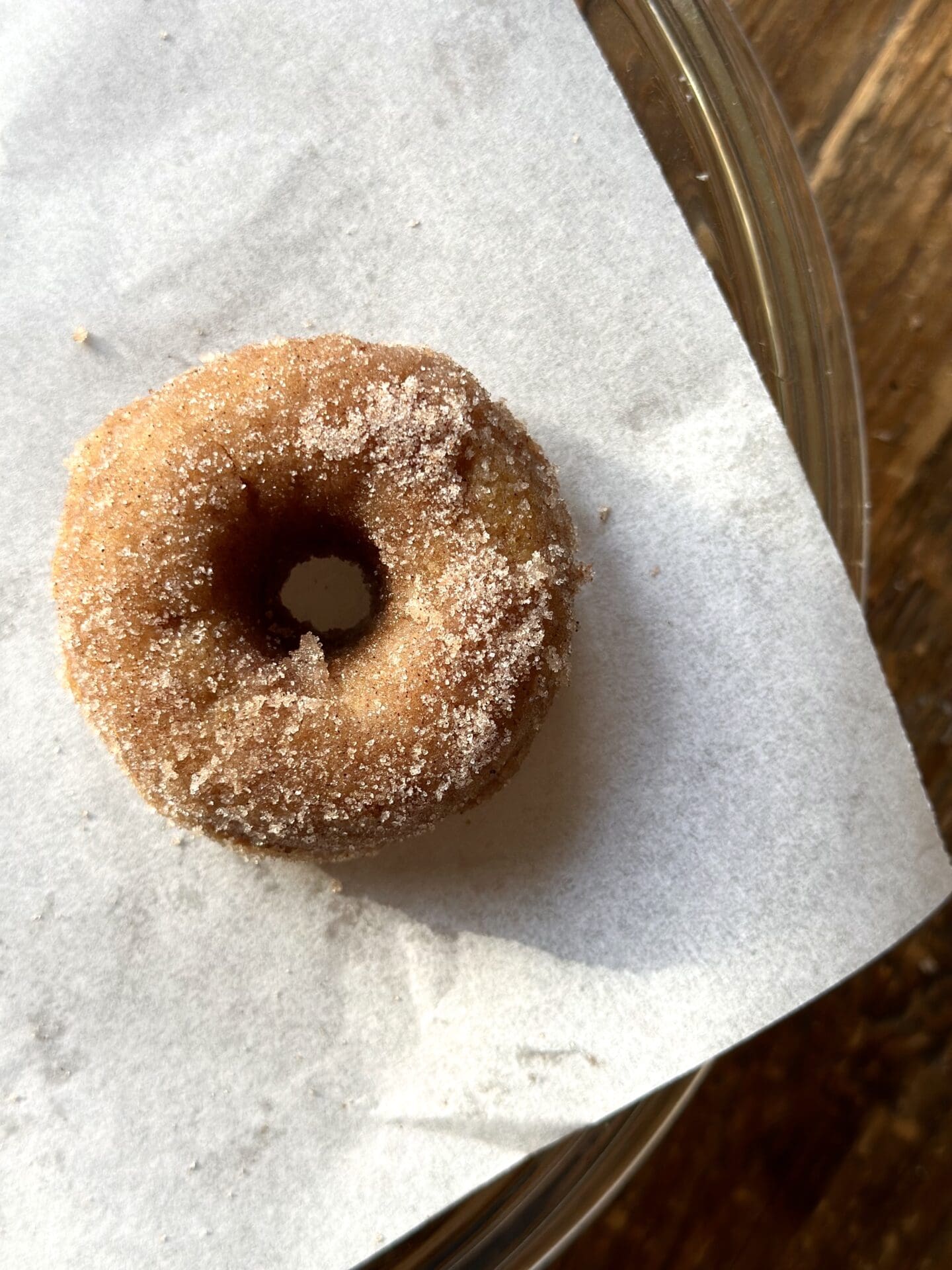 IMG_0002 A single cinnamon sugar donut is seen from above on a piece of white parchment paper
