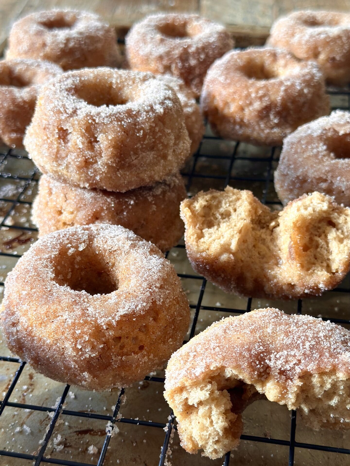 IMG_0005 Homemade old fashioned baked cinnamon sugar donuts are stacked on a cooling rack.