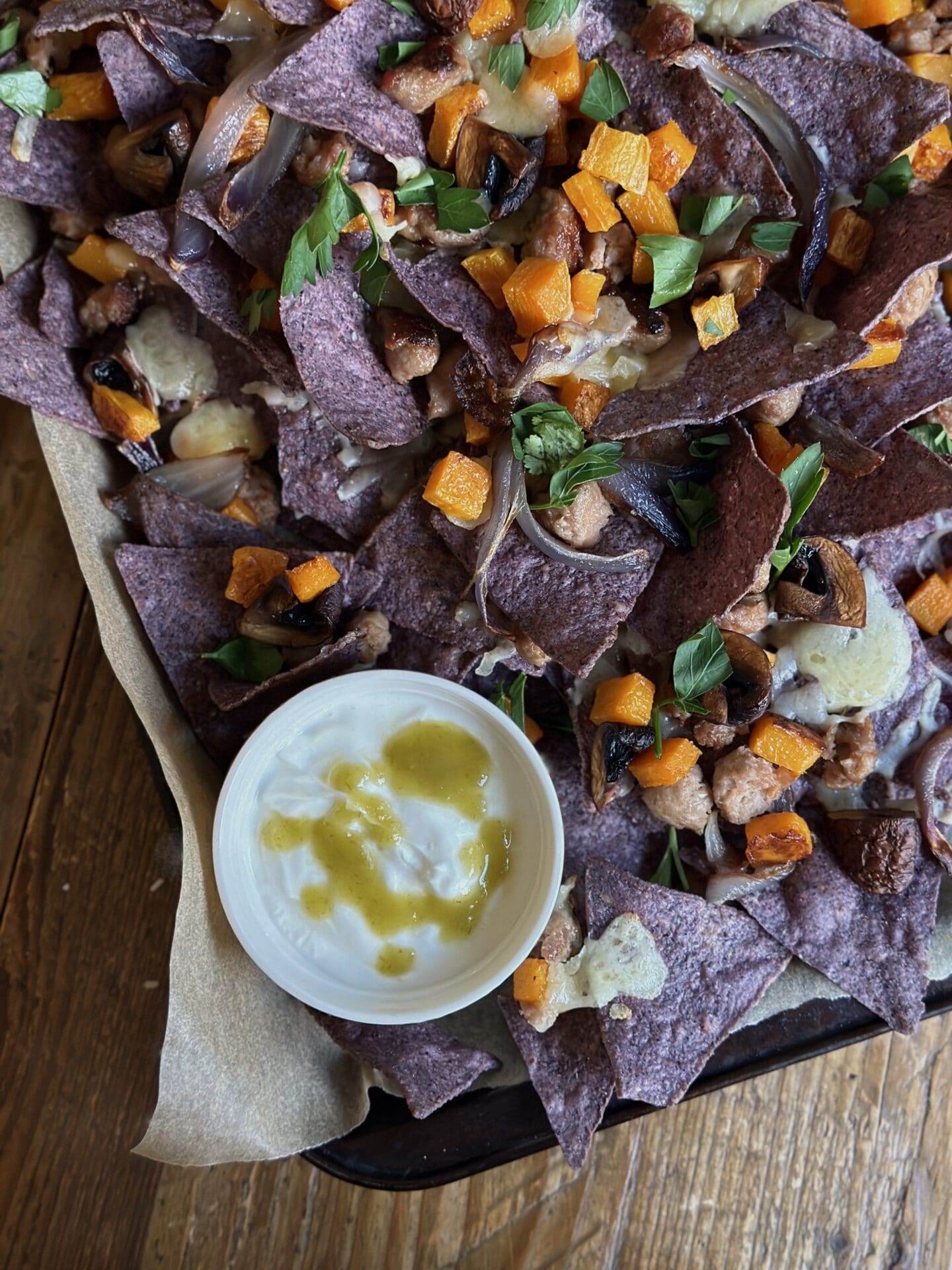IMG_0297 A tray of homemade blue corn harvest nachos is seen from above with a dish of jalapeño drizzled sour cream