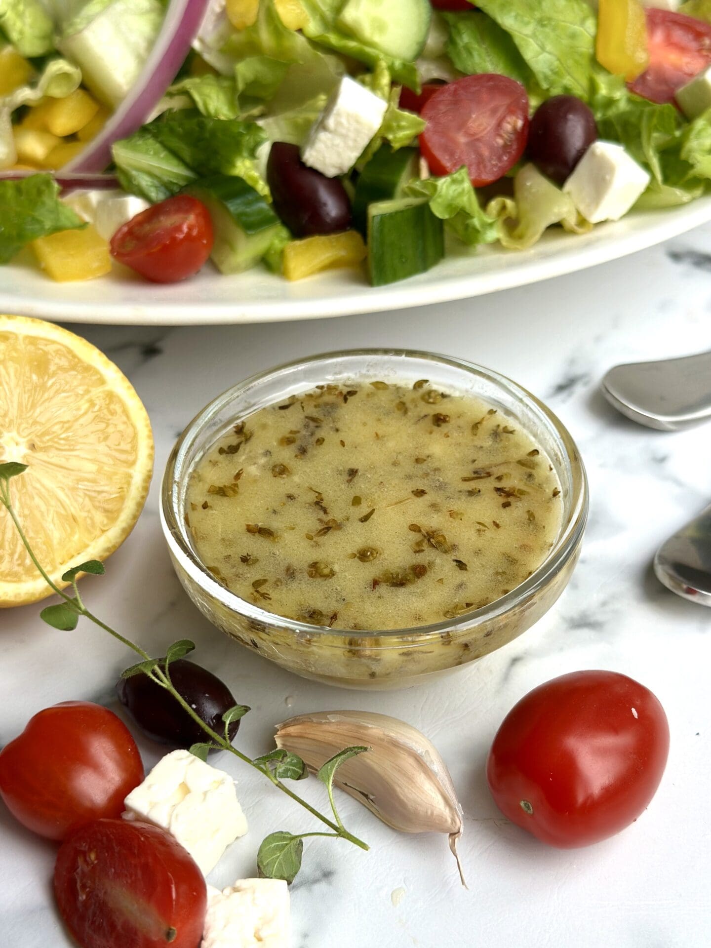 IMG_0476 a bowl of Greek salad dressing sits on a white marble counter with a Greek salad seen in the background