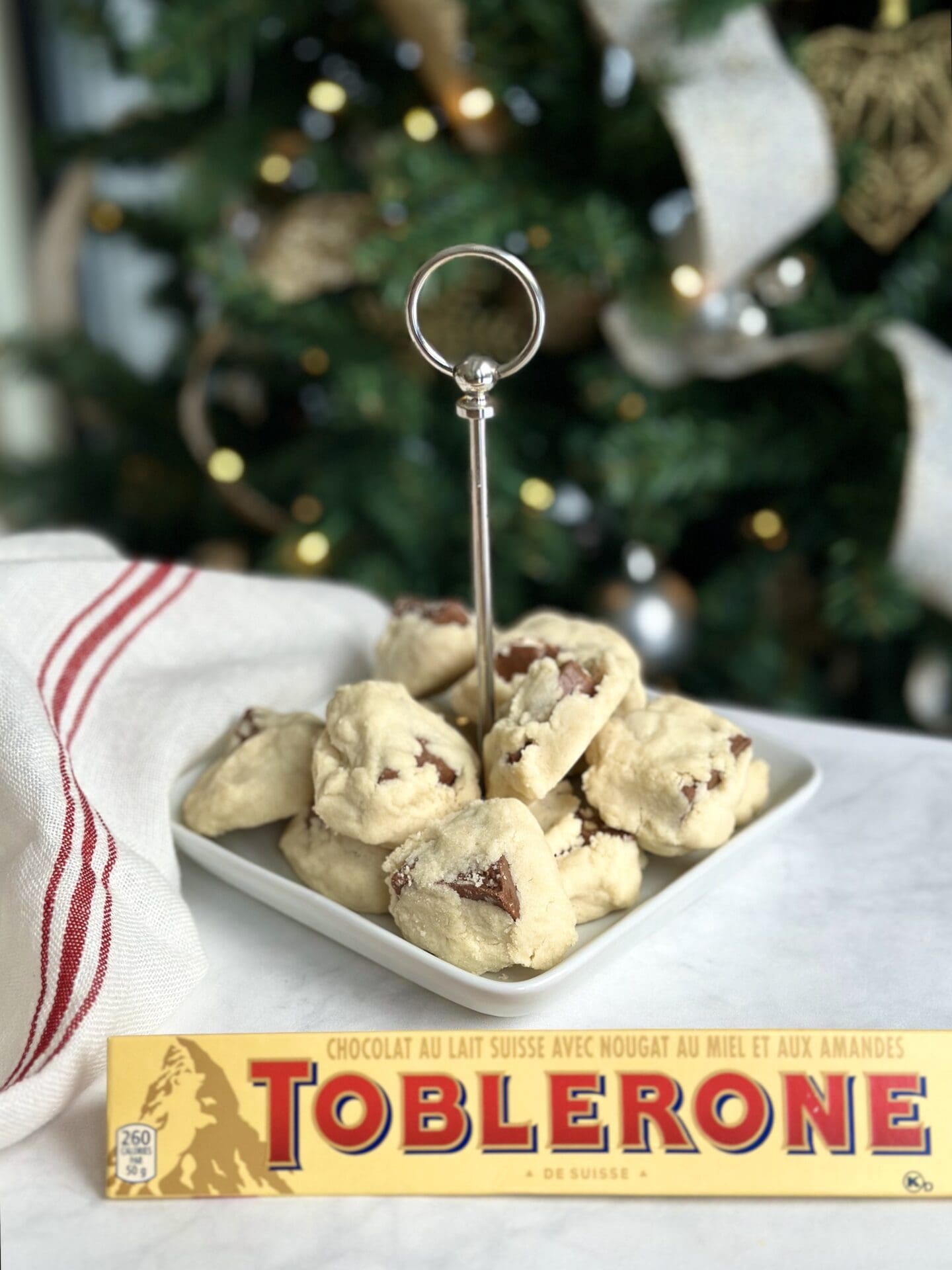 A plate of Toblerone shortbread cookies is seen in front of a Christmas tree