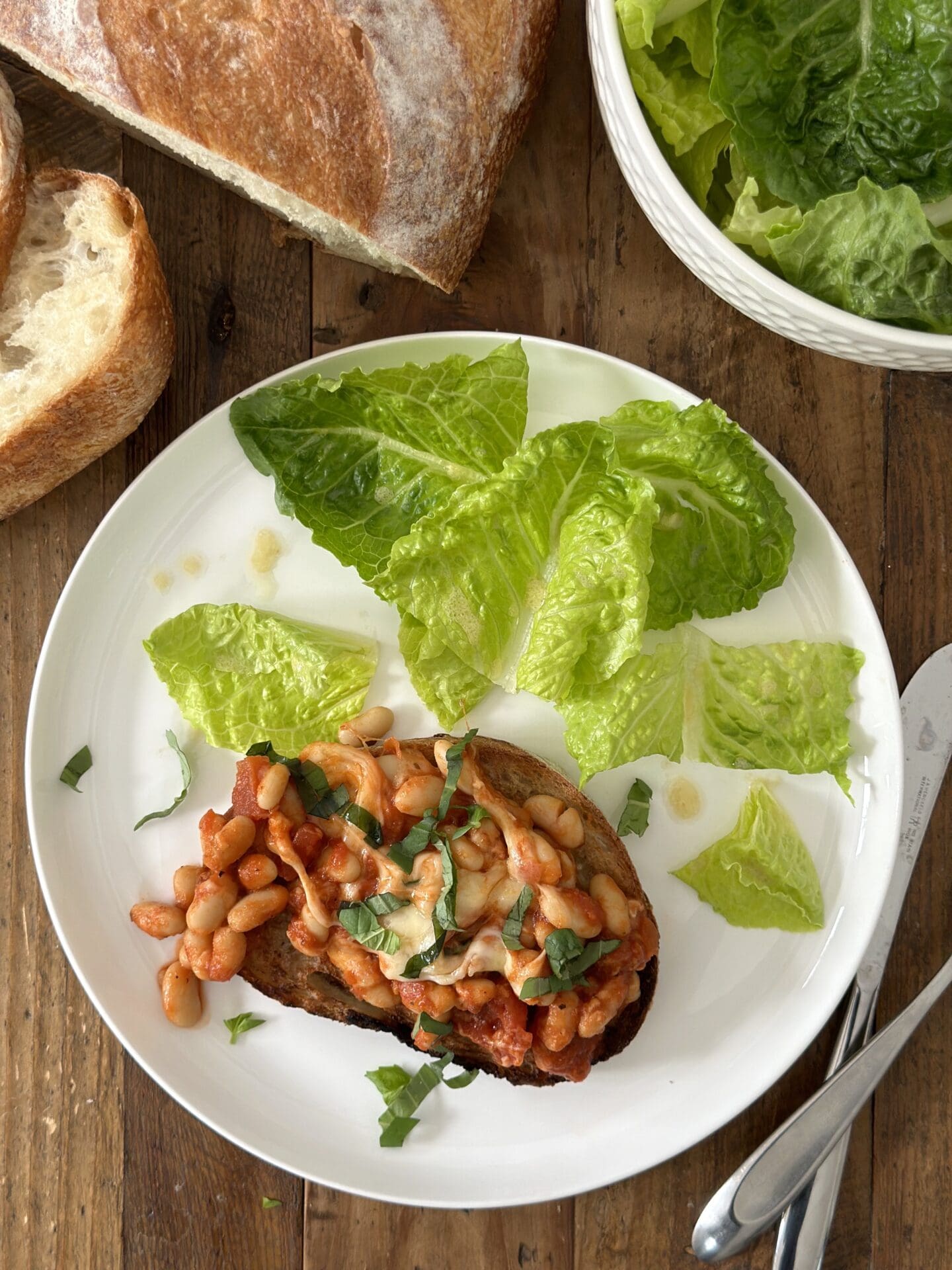 A plate is seen from above with Easy Cheesy Beans on a slice of garlic toast with a side of green salad