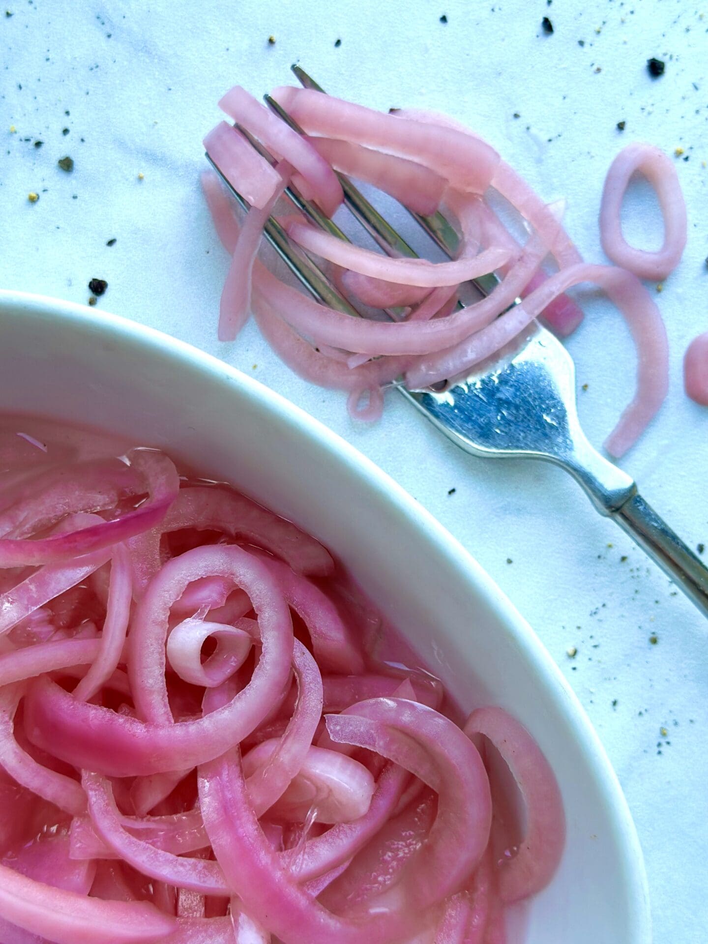 IMG_1268 A dish of bright pink pickled red onions is seen from above with a fork