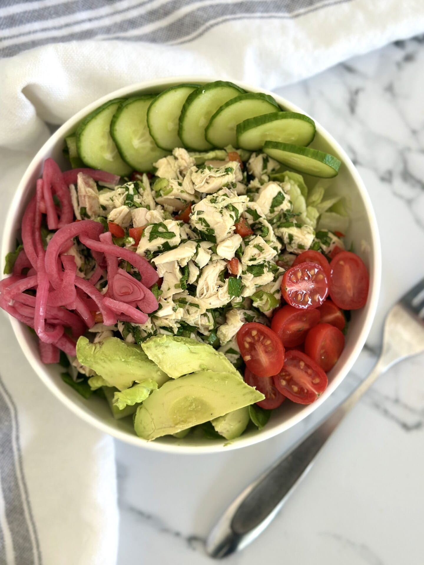 IMG_1569 A green salad is topped with mounds of cherry tomatoes, avocado, cucumber, pickled red onion and a large scoop of chimichurri chicken salad
