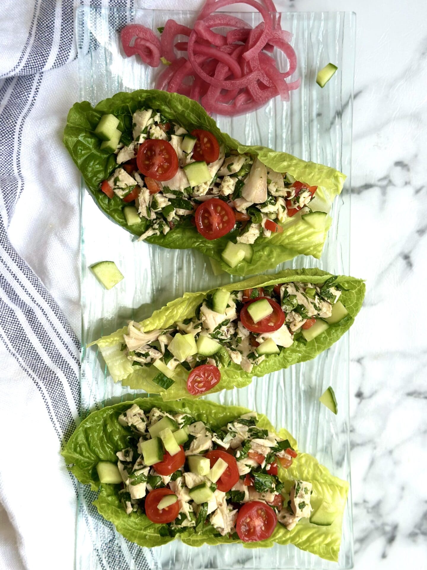 IMG_1582 A trio of romaine lettuce leaves are stuffed with chimichurri chicken salad and served on a glass plate