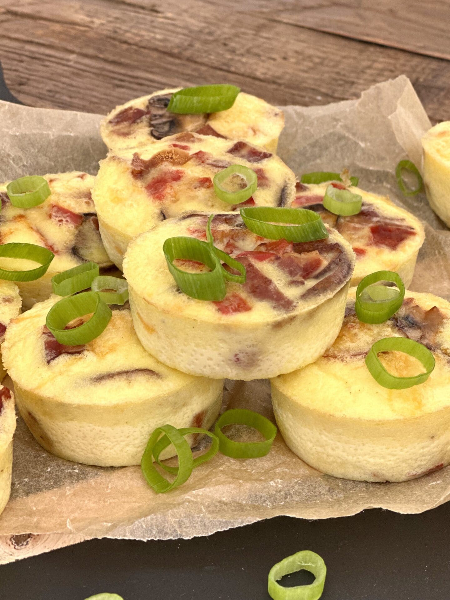 IMG_1857 Oven baked egg bites with bacon, mushroom and peppers are seen from the side, stacked on a parchment lined serving platter