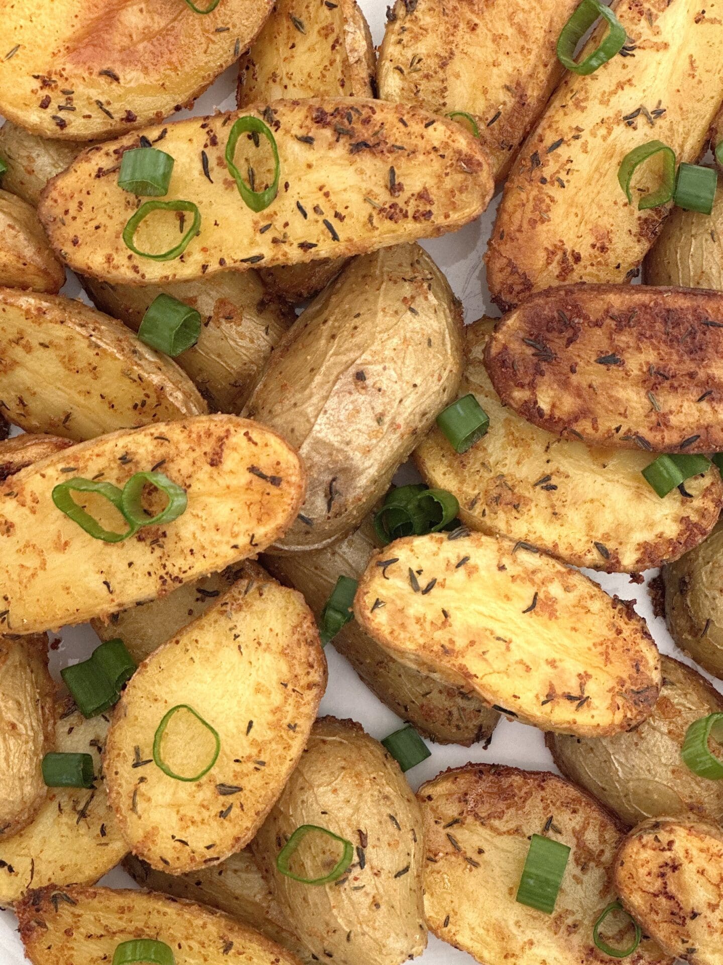 IMG_2041 Golden roasted fingerling potatoes are seen in close up from above, garnished with chopped green onions