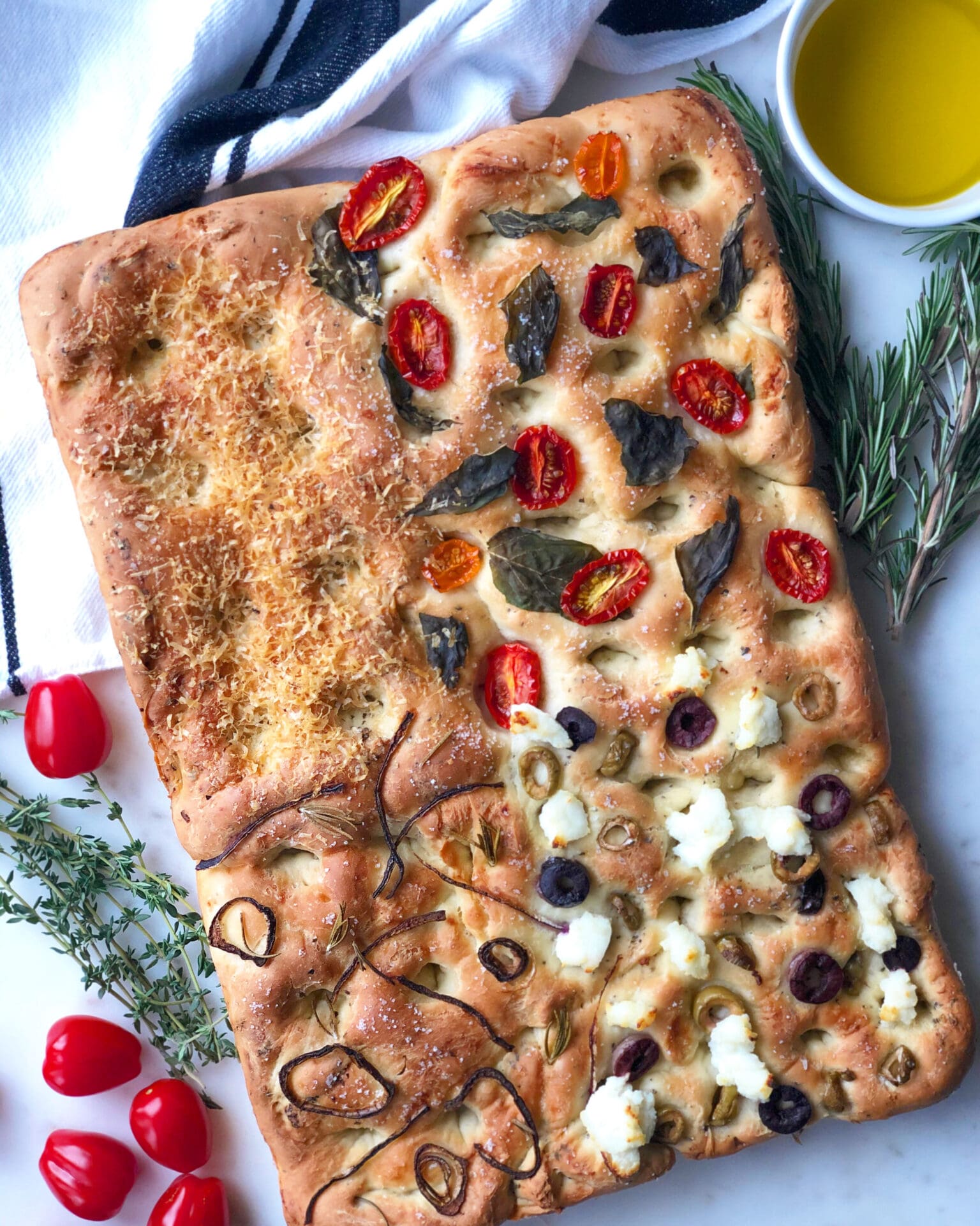 A4DD33D5-D06A-47F8-8FF1-A669A91A5E86 A rectangular focaccia bread is divided into 4 sections, each section topped with a different selection of vegetables, meats and cheeses