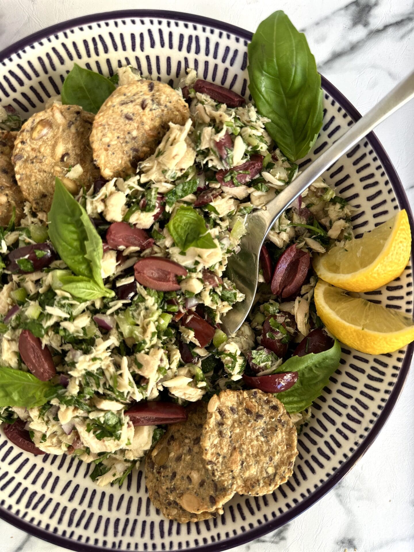 IMG_3488 A bowl of Italian tuna salad is seen from above, surrounded by crackers, black olives and lemon wedges