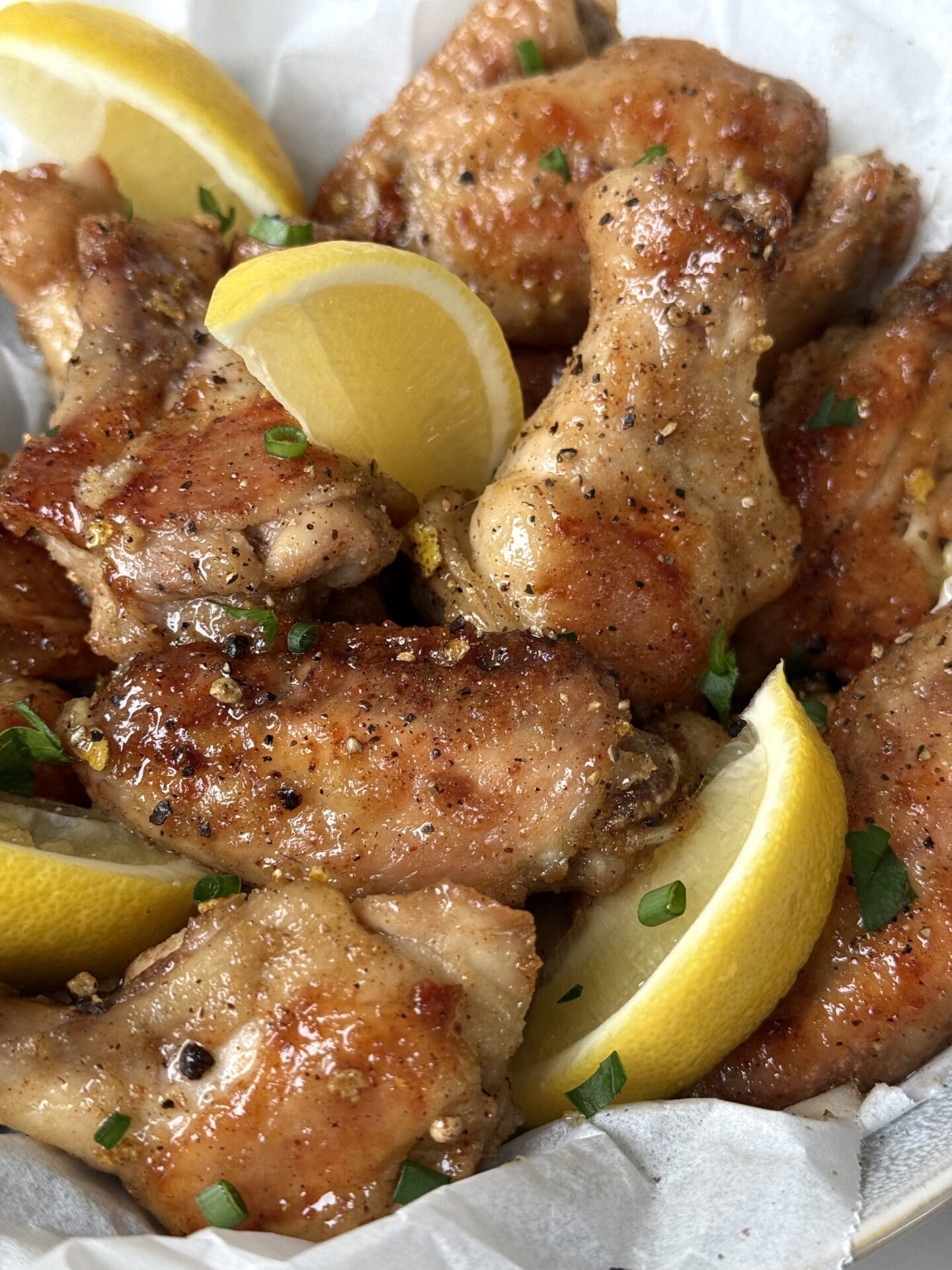 IMG_4263 Sweet and Tangy Lemon Pepper Chicken Wings are seen from above, garnished with lemon wedges and fresh parsley and chives