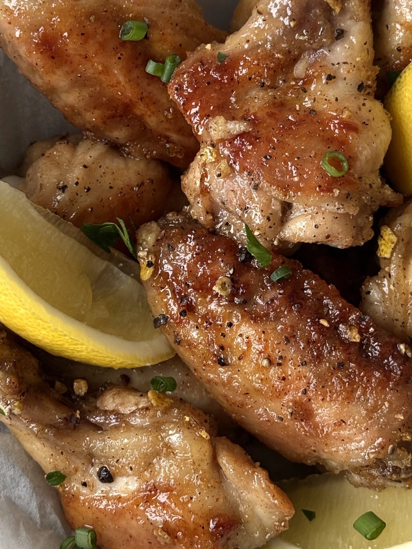 IMG_4269 Crisp and golden Lemon Pepper Chicken Wings are seen close up, showing flecks of lemon zest, black pepper and fresh herbs.