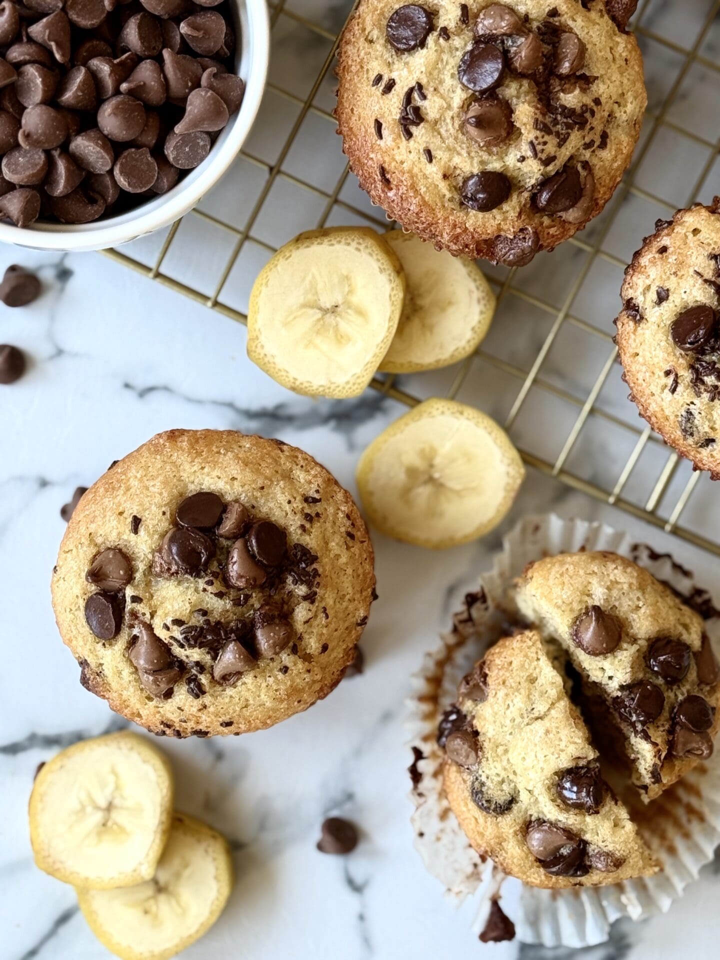 IMG_4518 Sour Cream Banana Chocolate Chip Muffins are seen from above, surrounded by banana slices and chocolate chips.