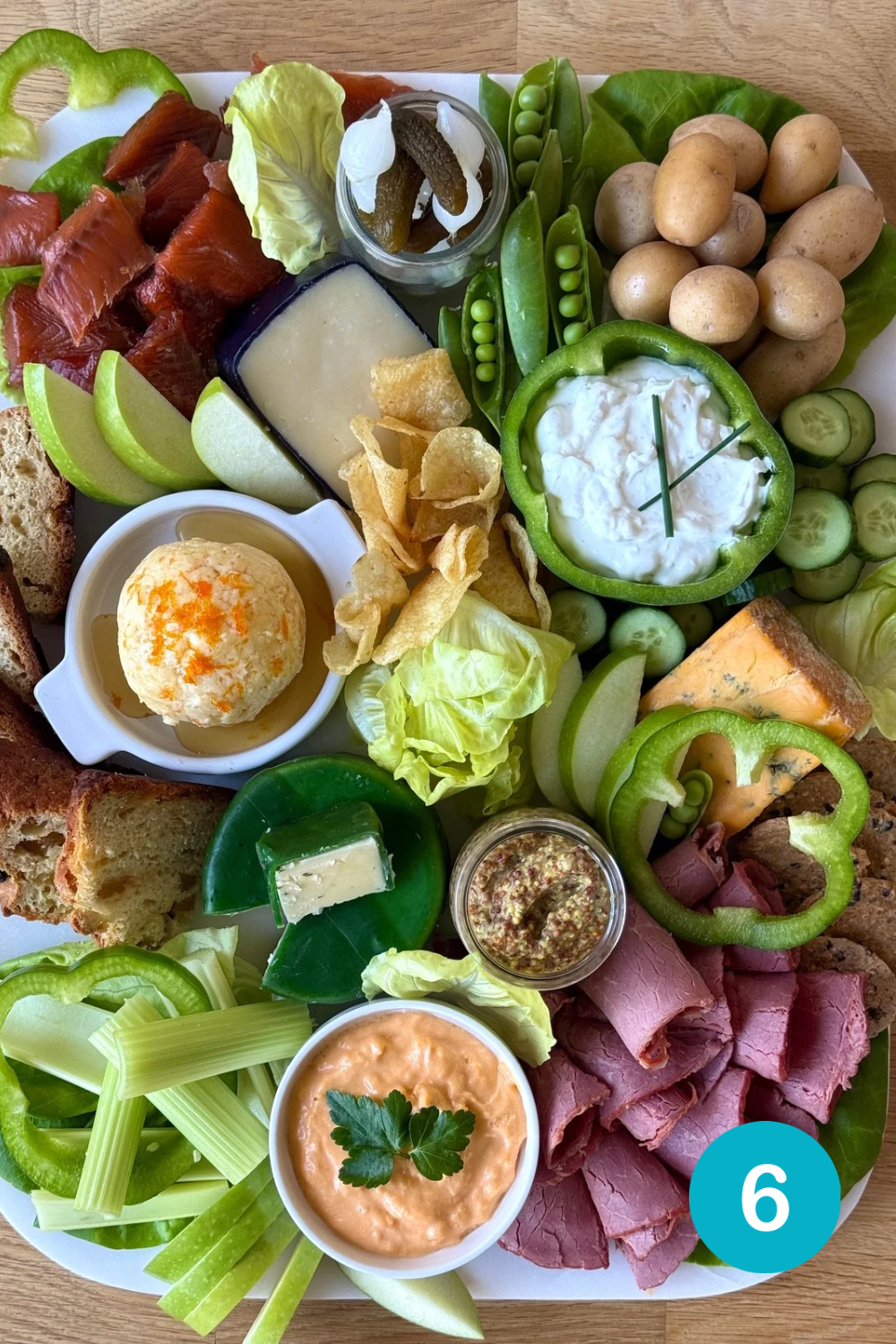 2E3C9CEE-D92D-4E0A-AE78-839825DD18C8 Step 6 in building a St Patrick's Day Charcuterie Board. Spaces on the board are filled in with green apple slices, Irish soda bread and crackers.