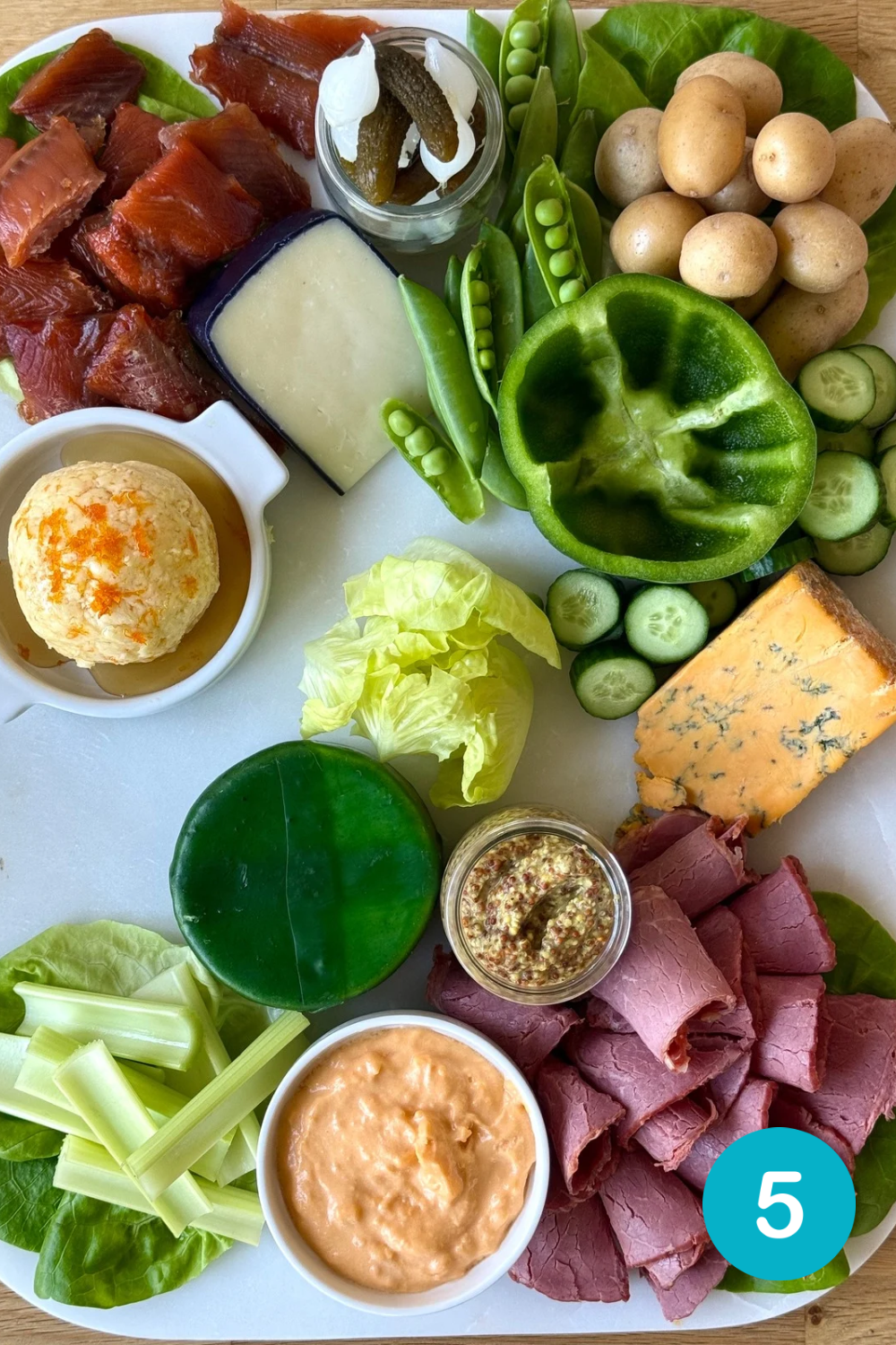 5F5D1594-BA71-4D4A-9323-06BA8CE456E3 Step 5 of building a St Patrick's Day Charcuterie Board. Green and white vegetables are added to the board.