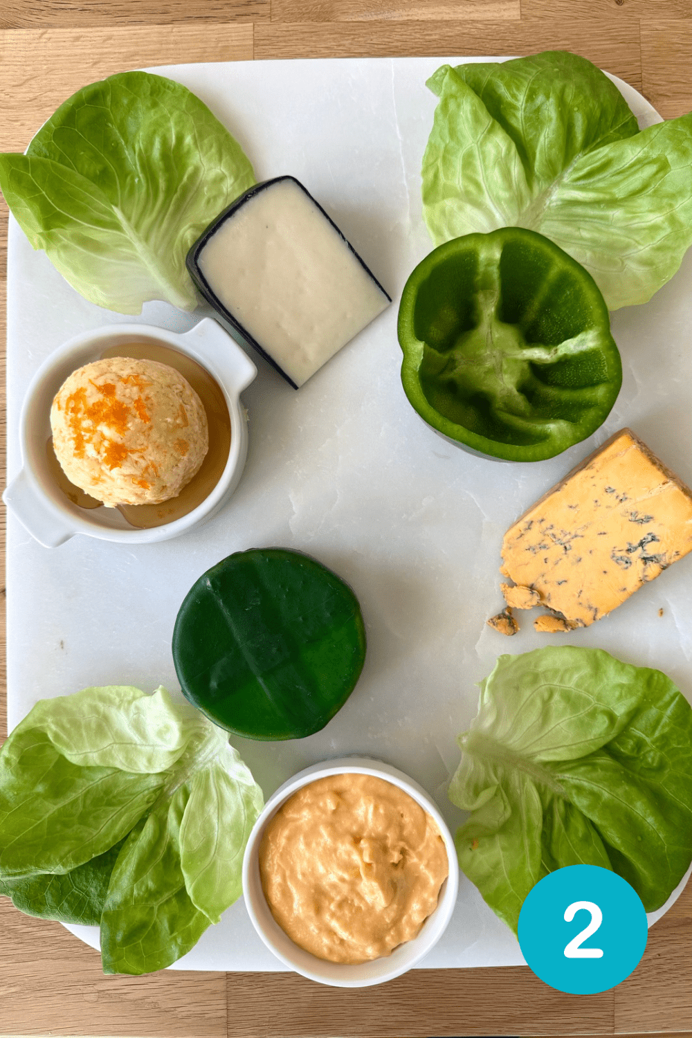 F56A9064-C14F-49B4-AD5C-6ABBF6DAD77B Step 2 in building a St Patrick's Day Charcuterie Board. Large items such as cheese wedges and dip bowls are added to the board.