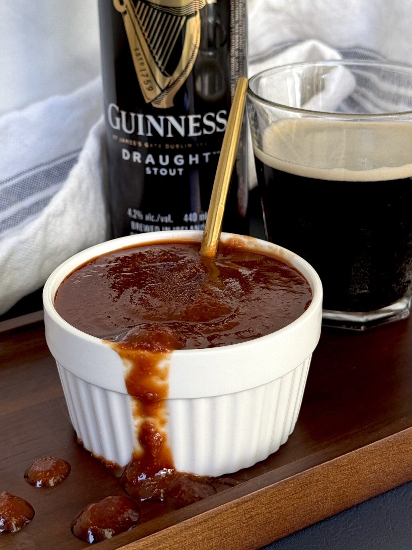 IMG_4763 A bowl of Guiness Barbecue Sauce overflows onto a wooden board. A can and glass of Guiness beer can be seen in the background.