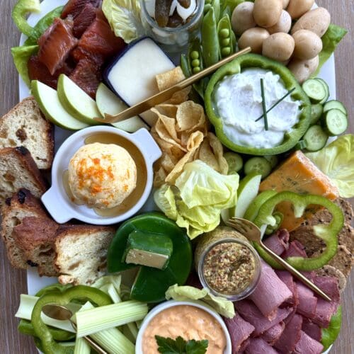 A lush St Patrick's Day Charcuterie board is seen from above. The board features cheeses, meats, vegetables and fruits in the colours of the Irish flag.