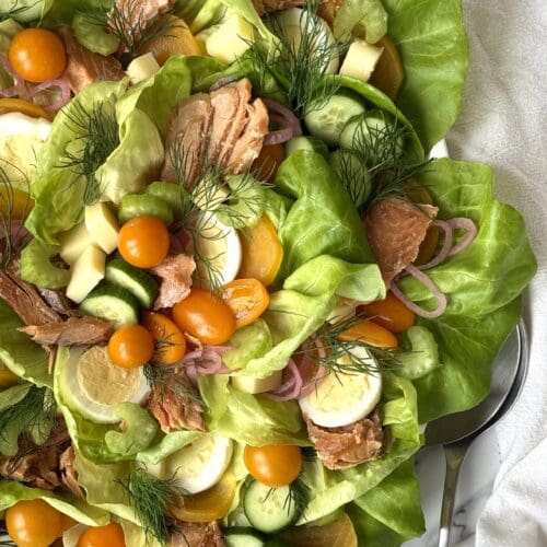 A platter of Irish Pub Salad with Hot Smoked Salmon fills most of the image, surrounded by crisp white table linens