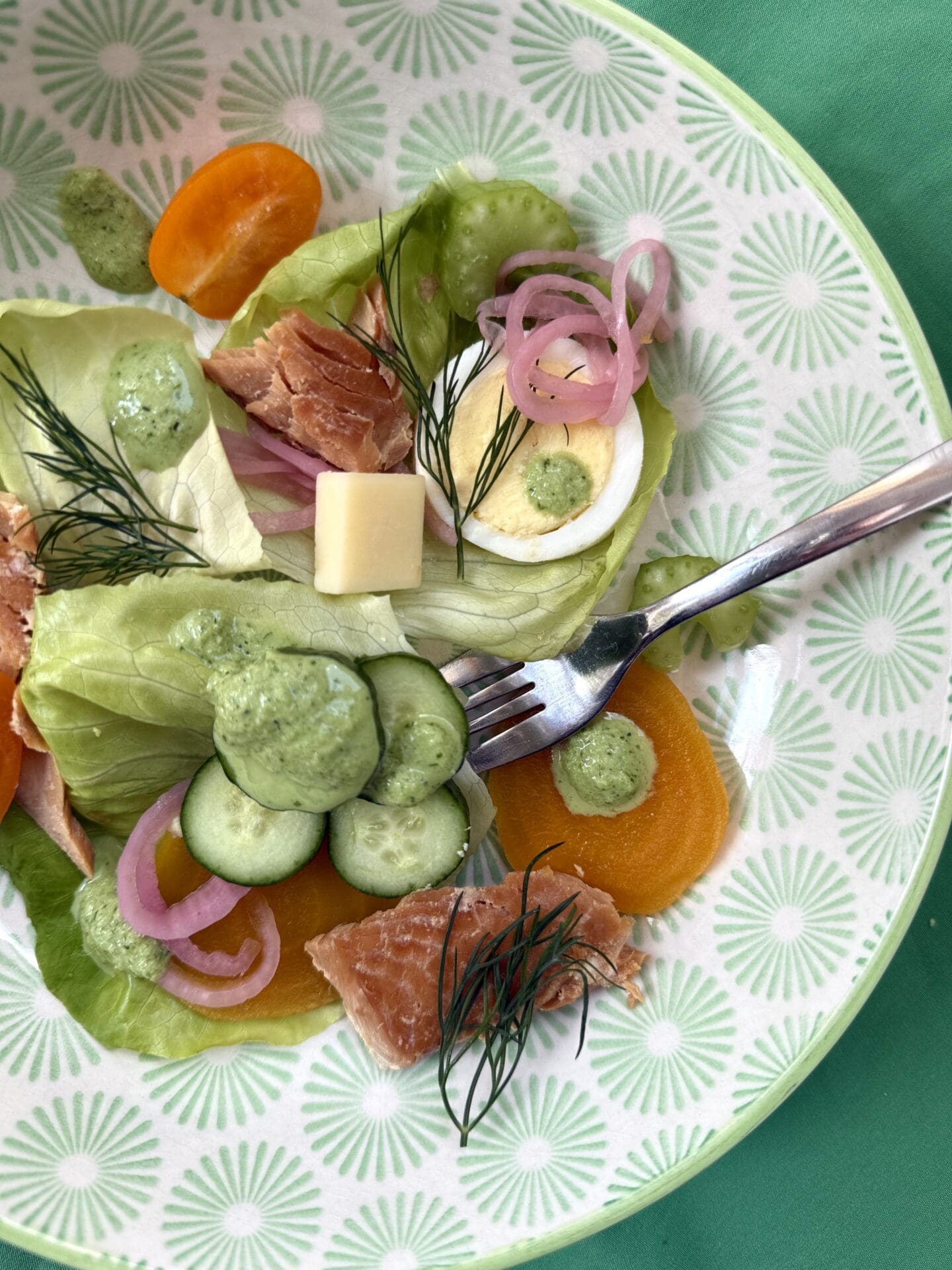 IMG_4938 An individual serving of Irish Pub Salad with Hot Smoked Salmon is seen from above in a green and white patterned bowl. The salad features tender green lettuce, crisp veggies, pickled golden beets, sliced eggs, hot smoked salmon and pickled red onions.