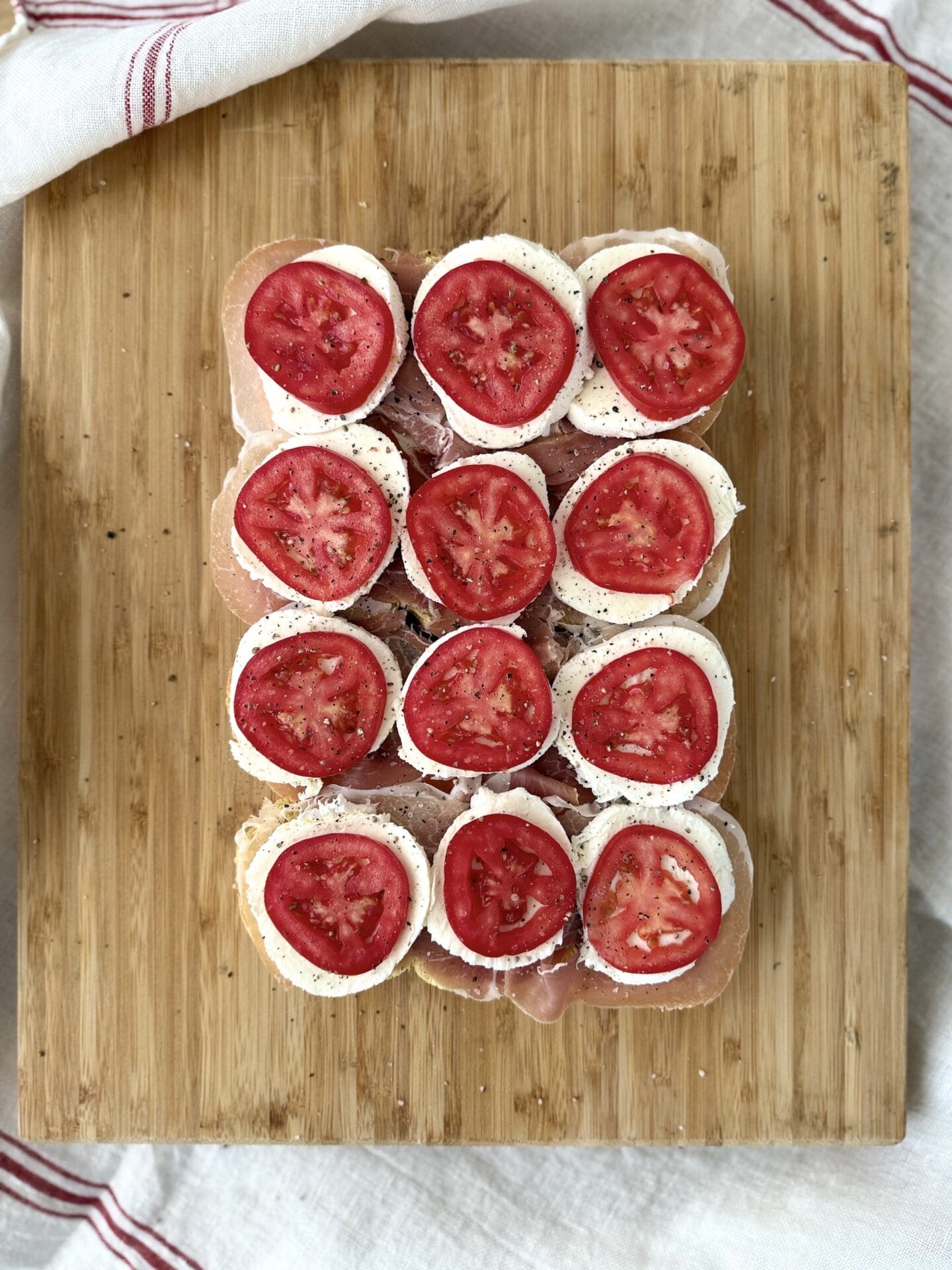 IMG_5007 Slices of bright red Roma tomatoes are stacked on Italian Antipasto Sliders in the fourth step.
