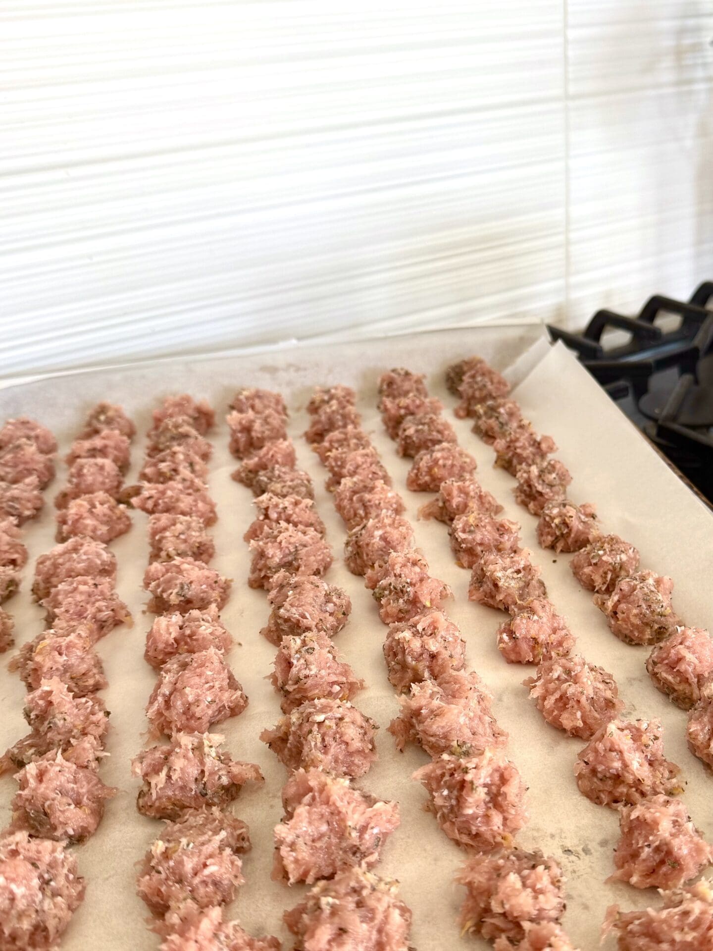 IMG_5665 A tray of turkey meatballs for Healthier Italian Wedding Soup is seen resting on a stovetop, waiting to be placed in a hot oven.