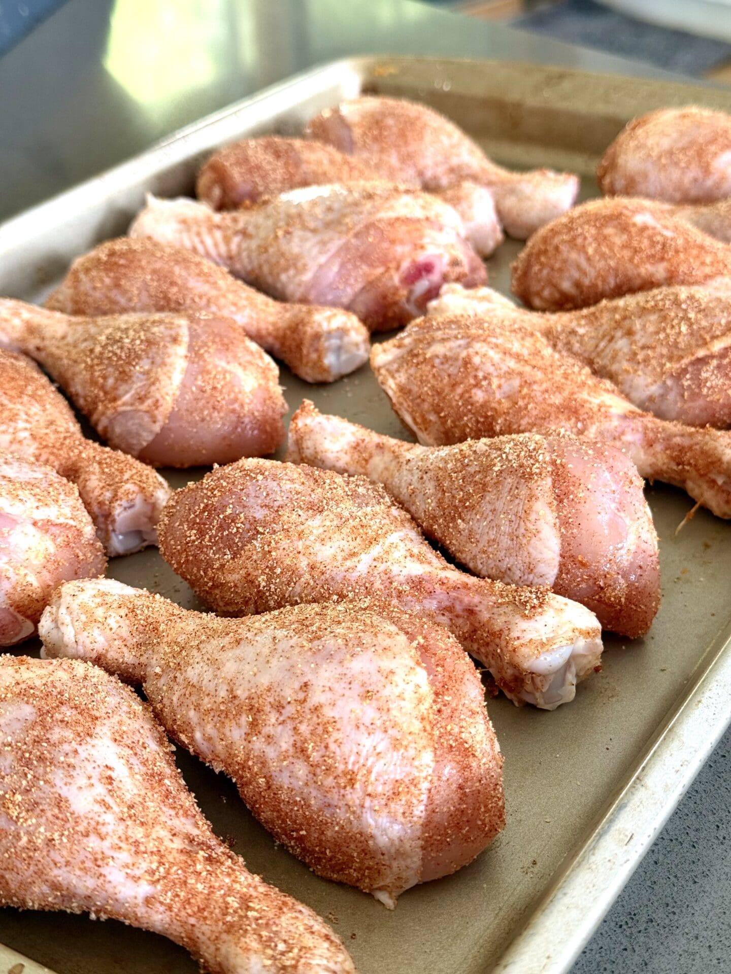 IMG_5913 A tray of chicken legs coated in a dry rub sits on the counter, ready to be grilled.