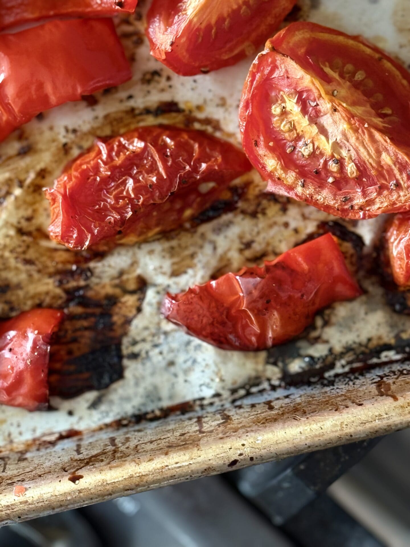 IMG_6807 Roasted tomatoes and red peppers are seen close up, cooling on a baking sheet before being added to roasted tomato and feta soup.