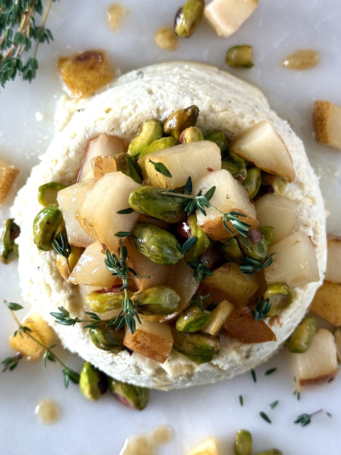 Pistachio and Pear Baked Ricotta is seen from above, displaying its beautiful caramelized pear and vibrant green pistachio topping.