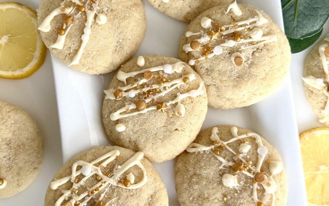 A platter of chewy and soft lemon sugar cookies is seen from above, dressed for the holidays with a drizzle of white chocolate and a dusting of gold sprinkles.