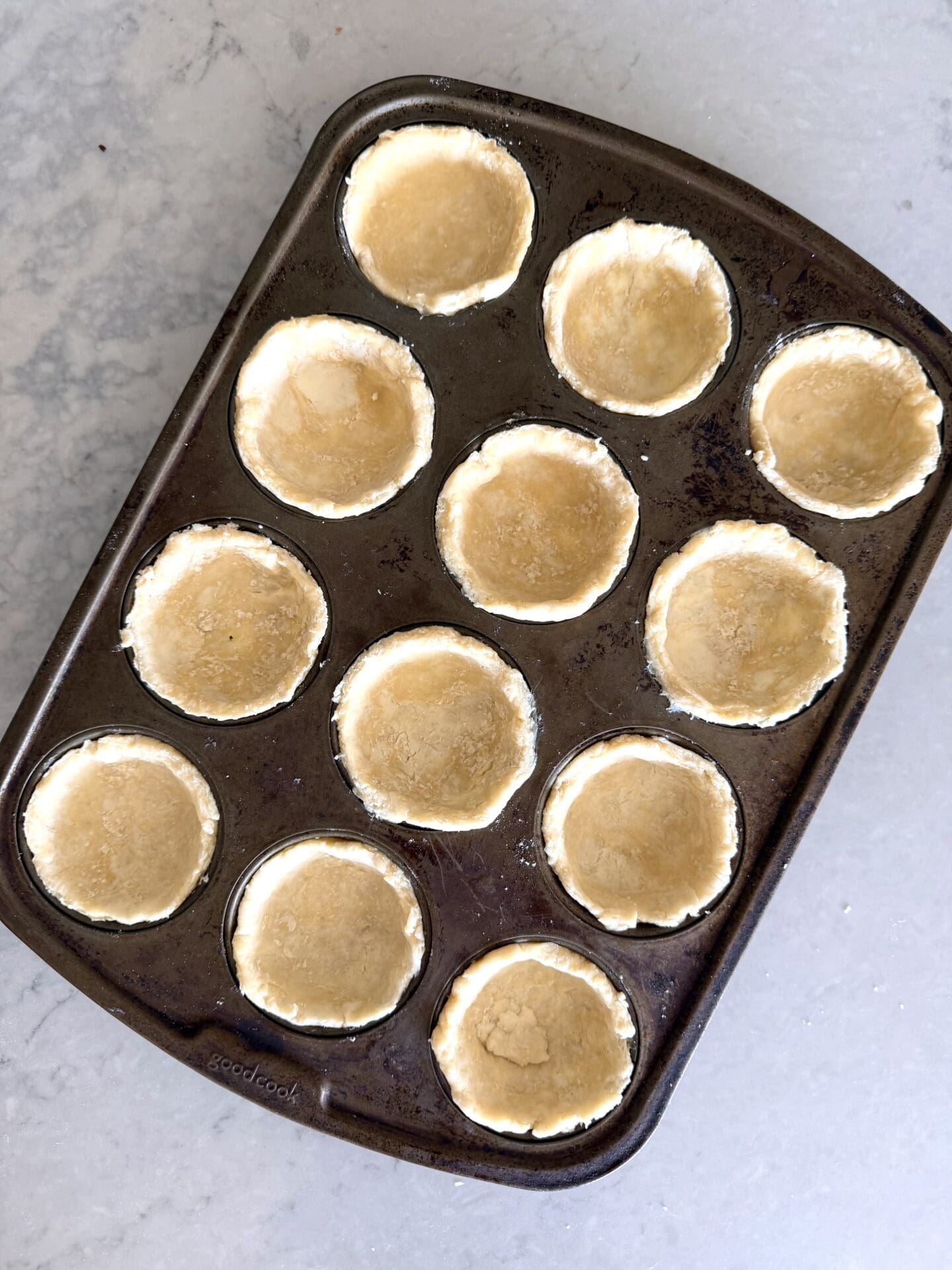 Rounds of pastry dough are pressed into a regular muffin pan.