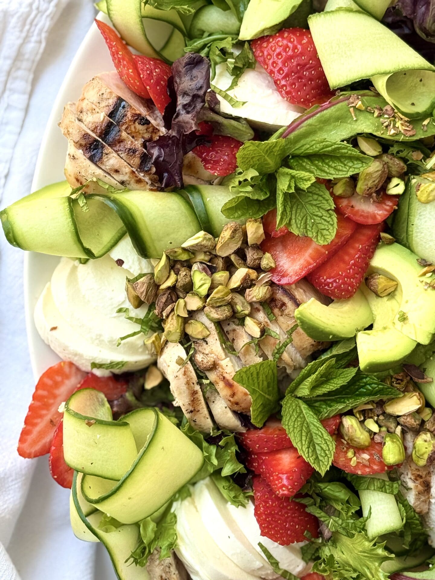 A close up photo of Strawberry Cucumber Salad with Grilled Lemon Chicken shows off its vibrant berries and crisp cucumbers curls.