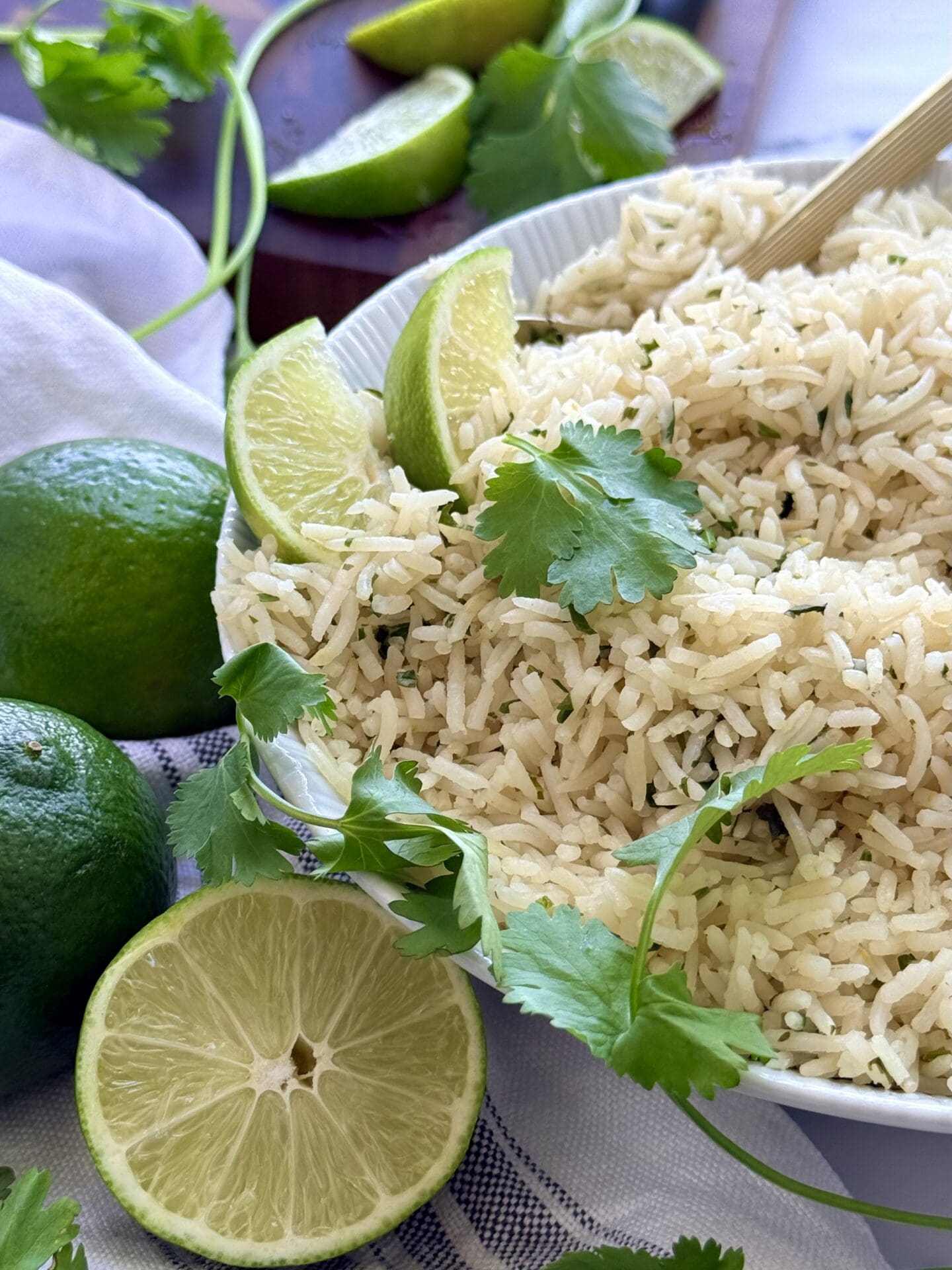 A bowl of cilantro lime rice slides into the frame from the right, giving the viewer a close look at the seasoned rice.  Cilantro leaves and fresh lime slices garnish the bowl.