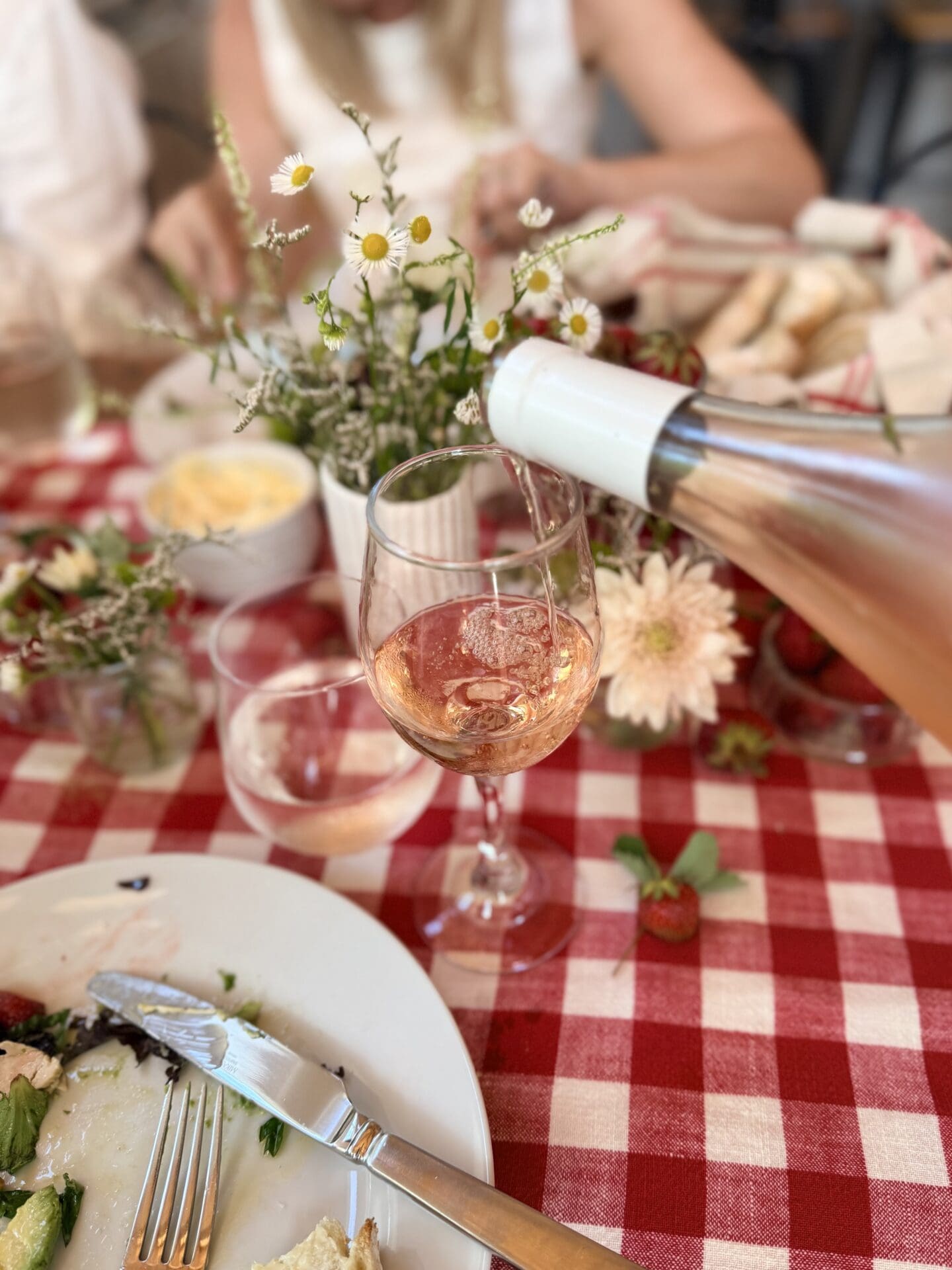 A bottle of rosé wine is poured into a glass at the strawberry social lunch.